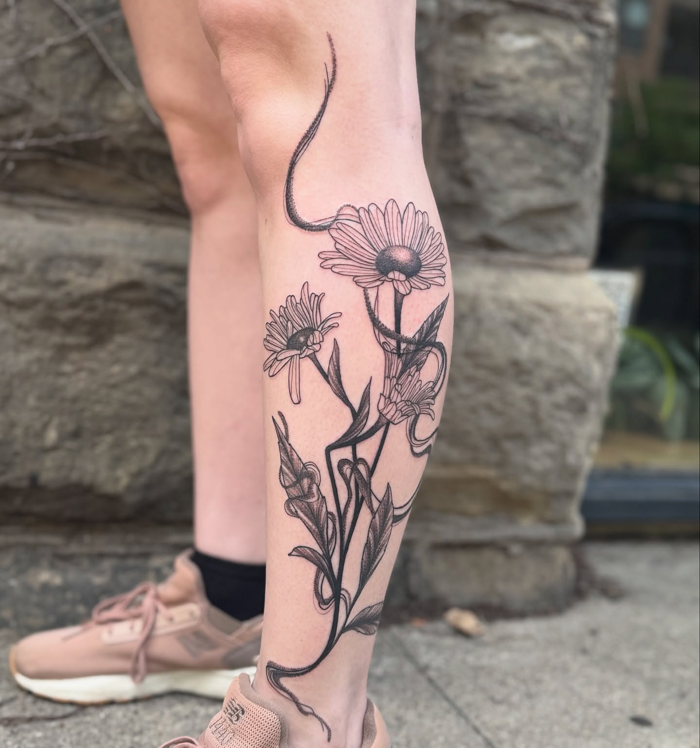 Daisies and snake black and grey tattoo on the calf by Sydney