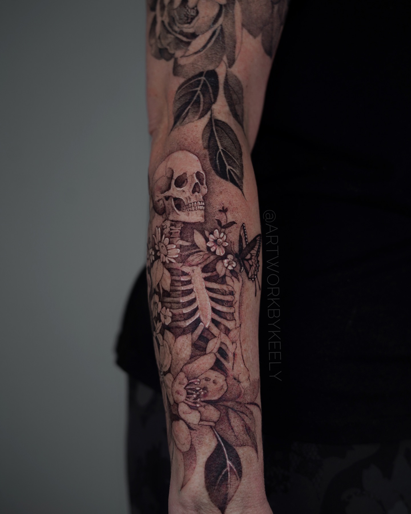 Skeleton with floral elements realism tattoo on the forearm by Keely Thompson