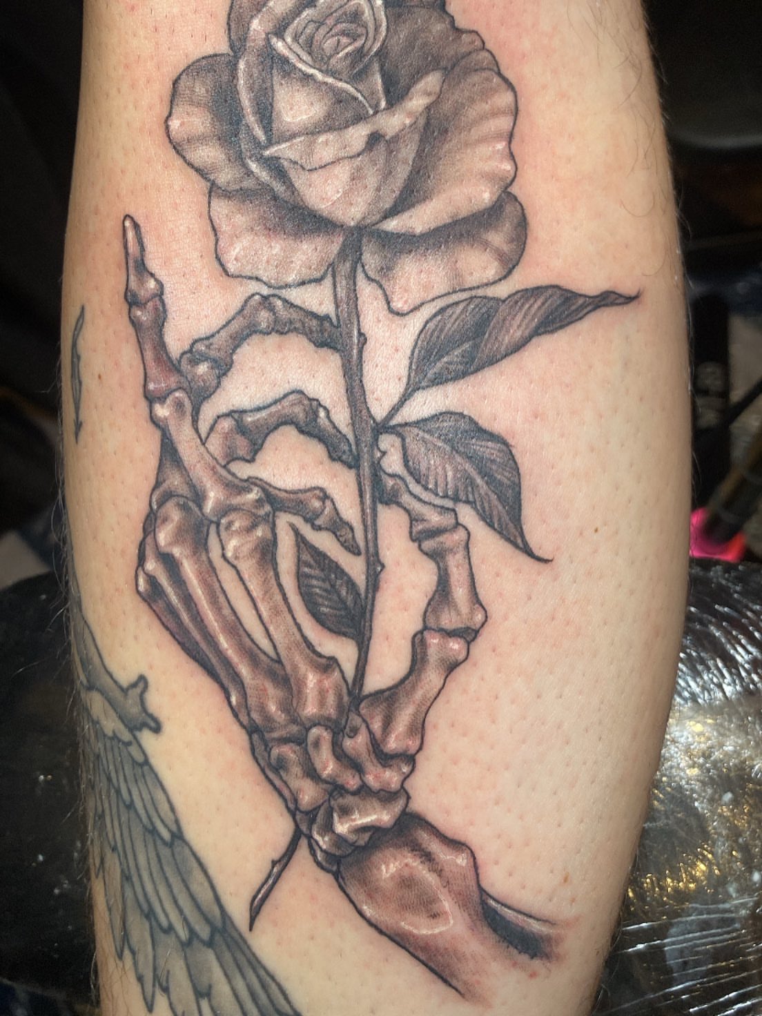 Skeleton hand holding rose realism tattoo on the forearm by Hecho En El Bronx