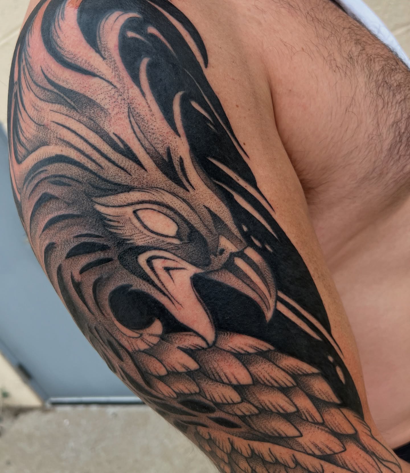 Owl black and grey tattoo on the upper arm by Nathan Garcia