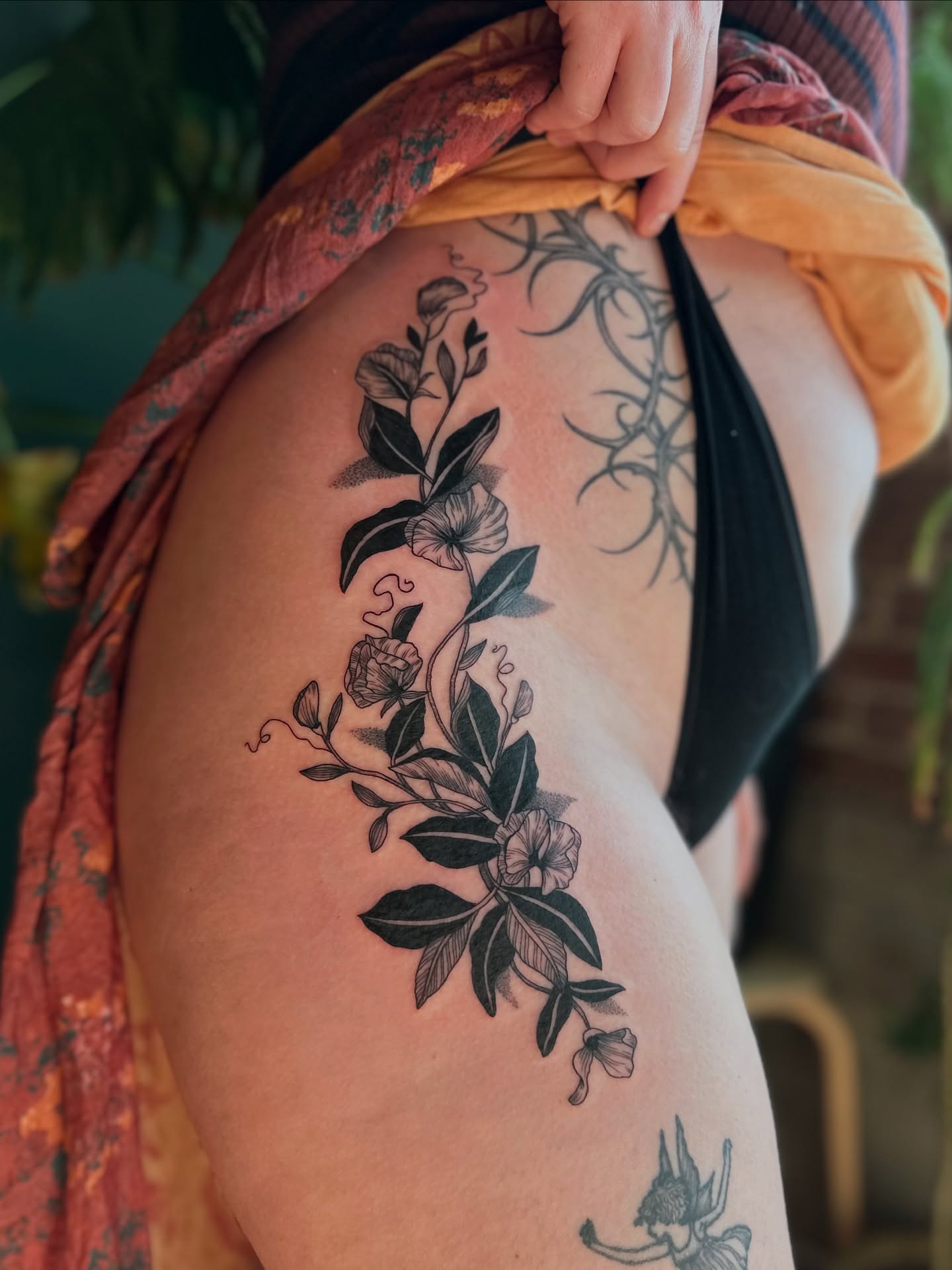 Floral vine black and grey tattoo on the thigh by Alexandra Gray