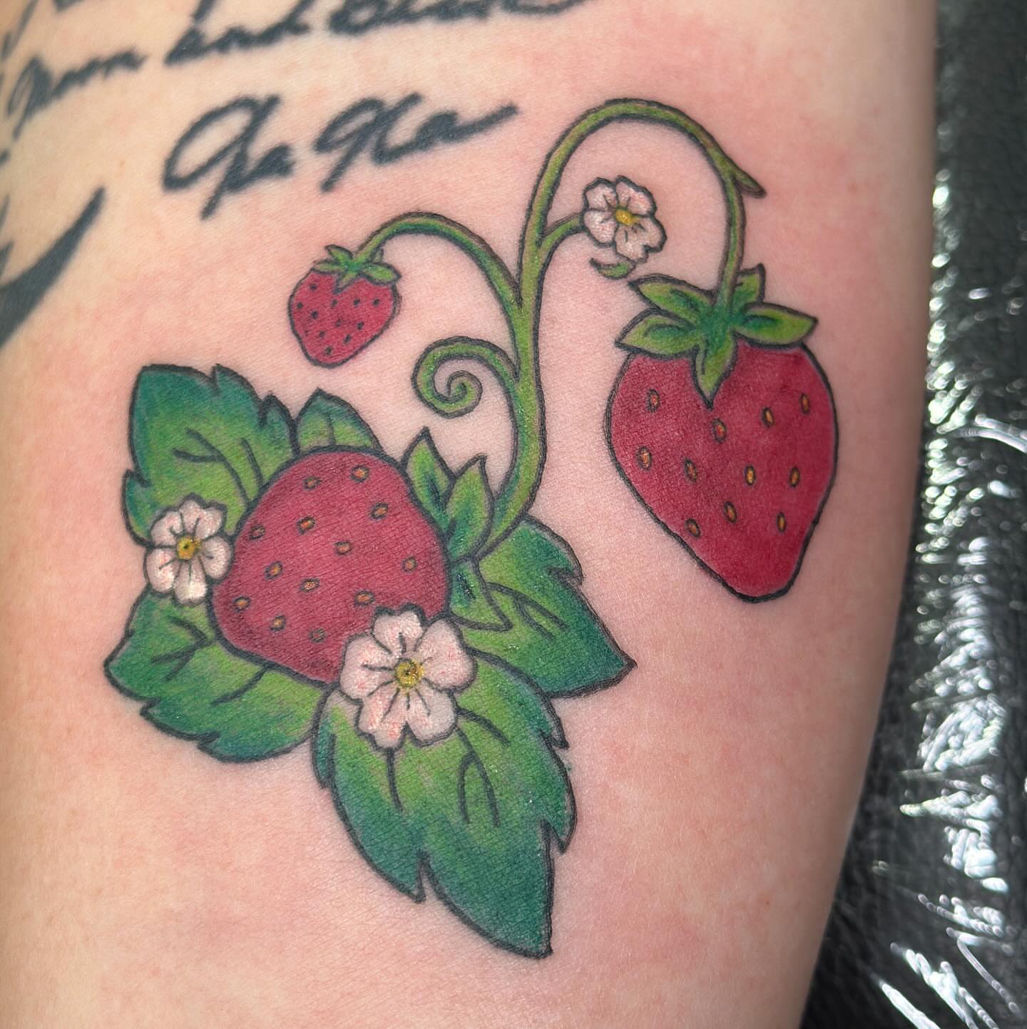 Strawberries and flowers American traditional tattoo on the upper arm by Zen Forbes