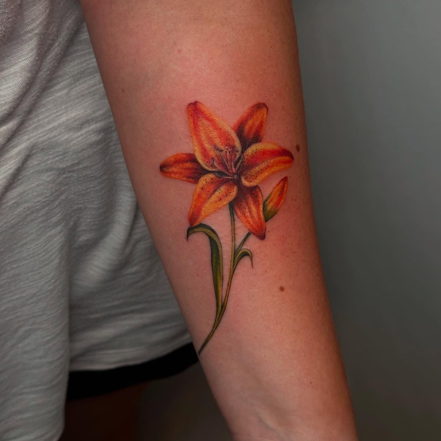 Orange lily realism tattoo on the forearm by 𓆏 Alyssa Carbonara 𓆏