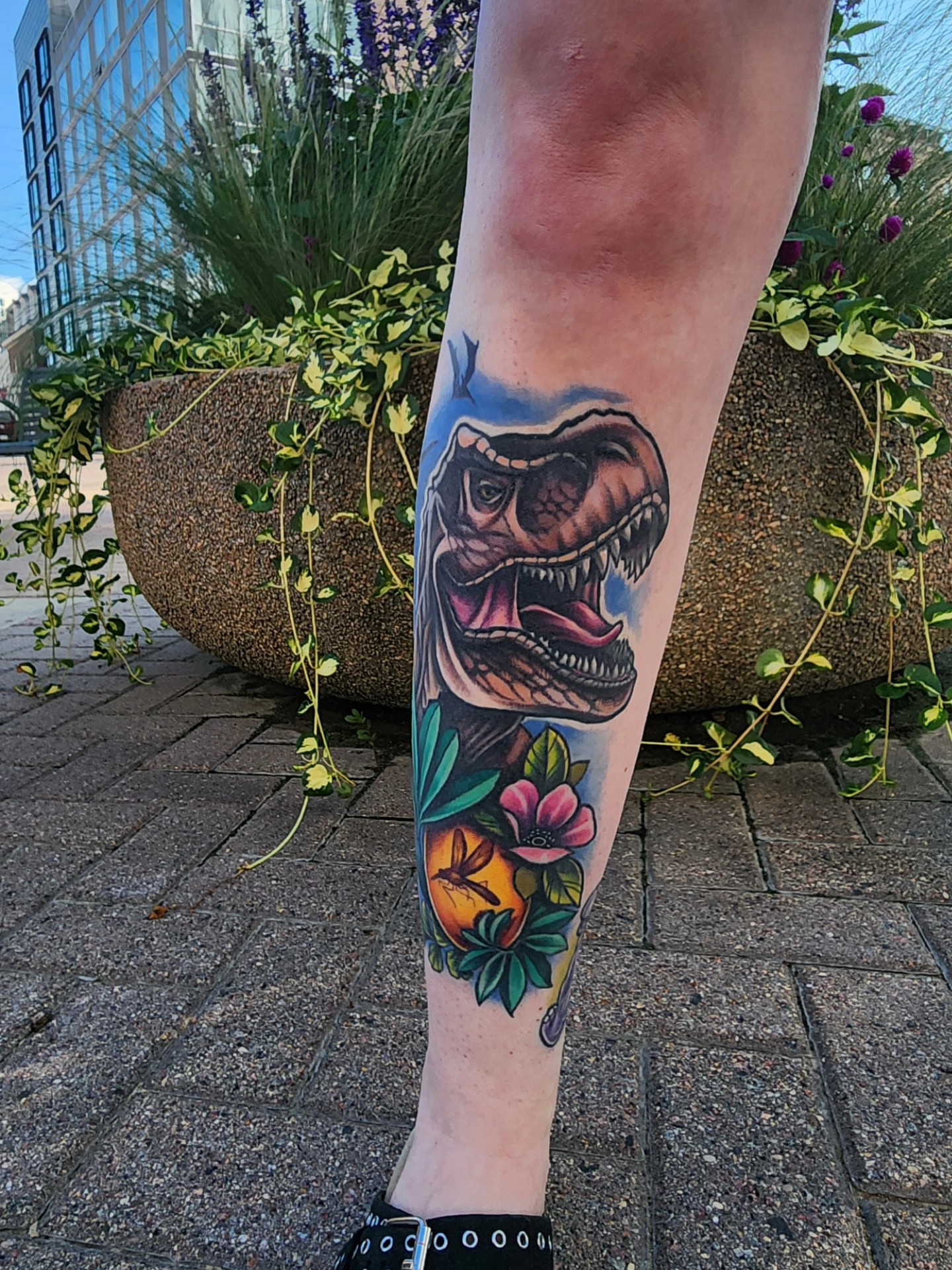 T-Rex and floral realism tattoo on the forearm by Shawna Goettsche