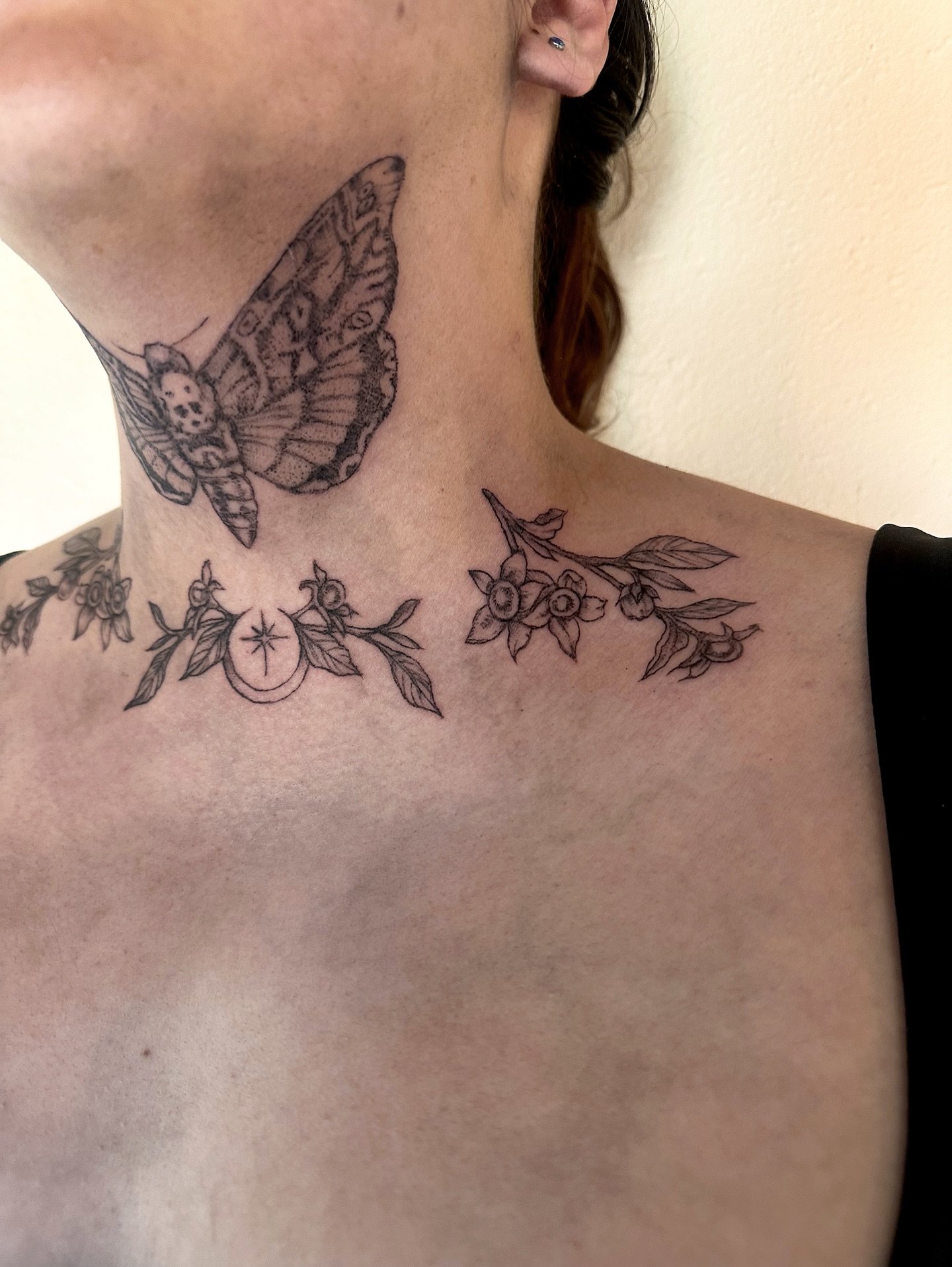 Butterfly and floral black and grey tattoo on the neck by kenzie hunter