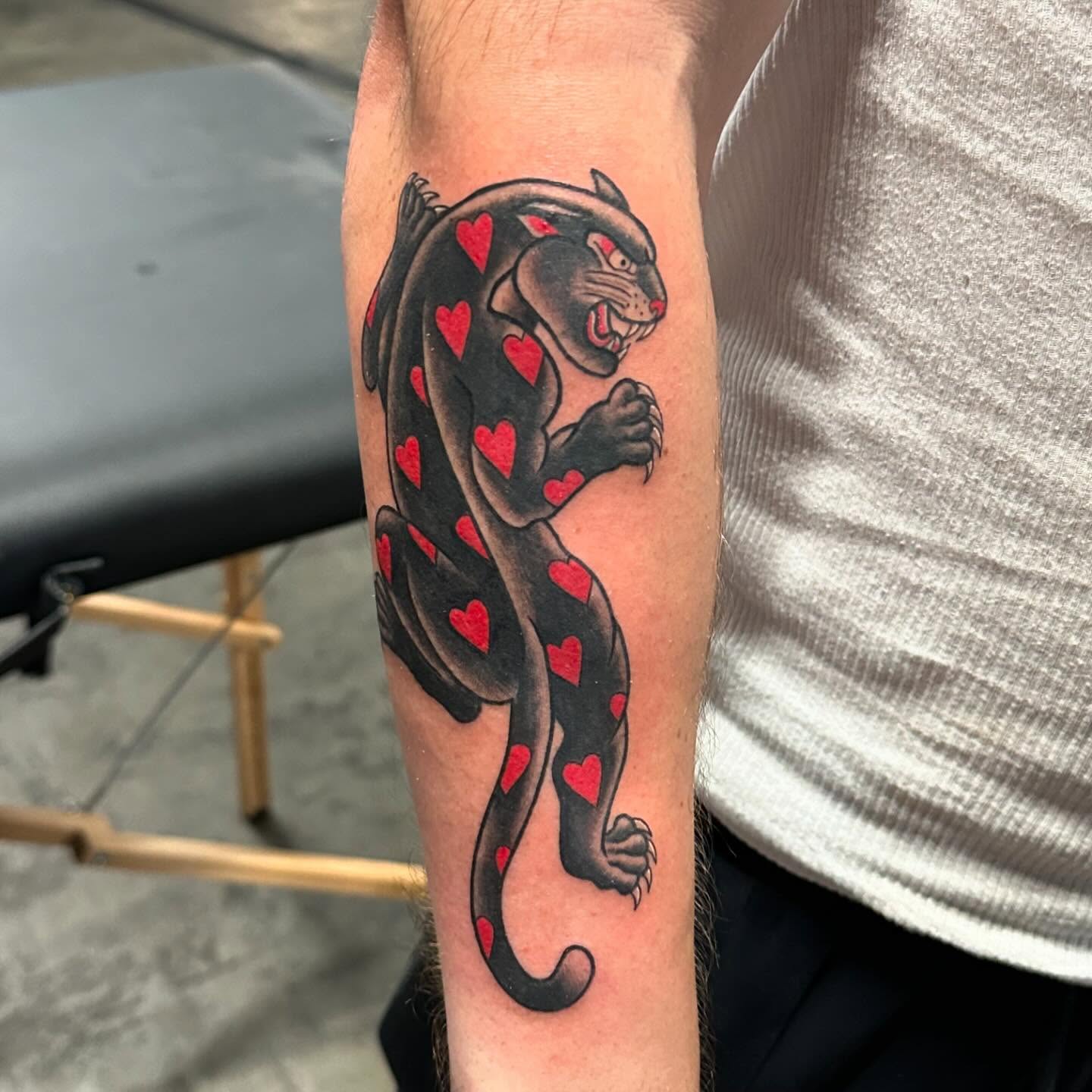 Panther with hearts American traditional tattoo on the forearm by Kerri Colello Sittenauer