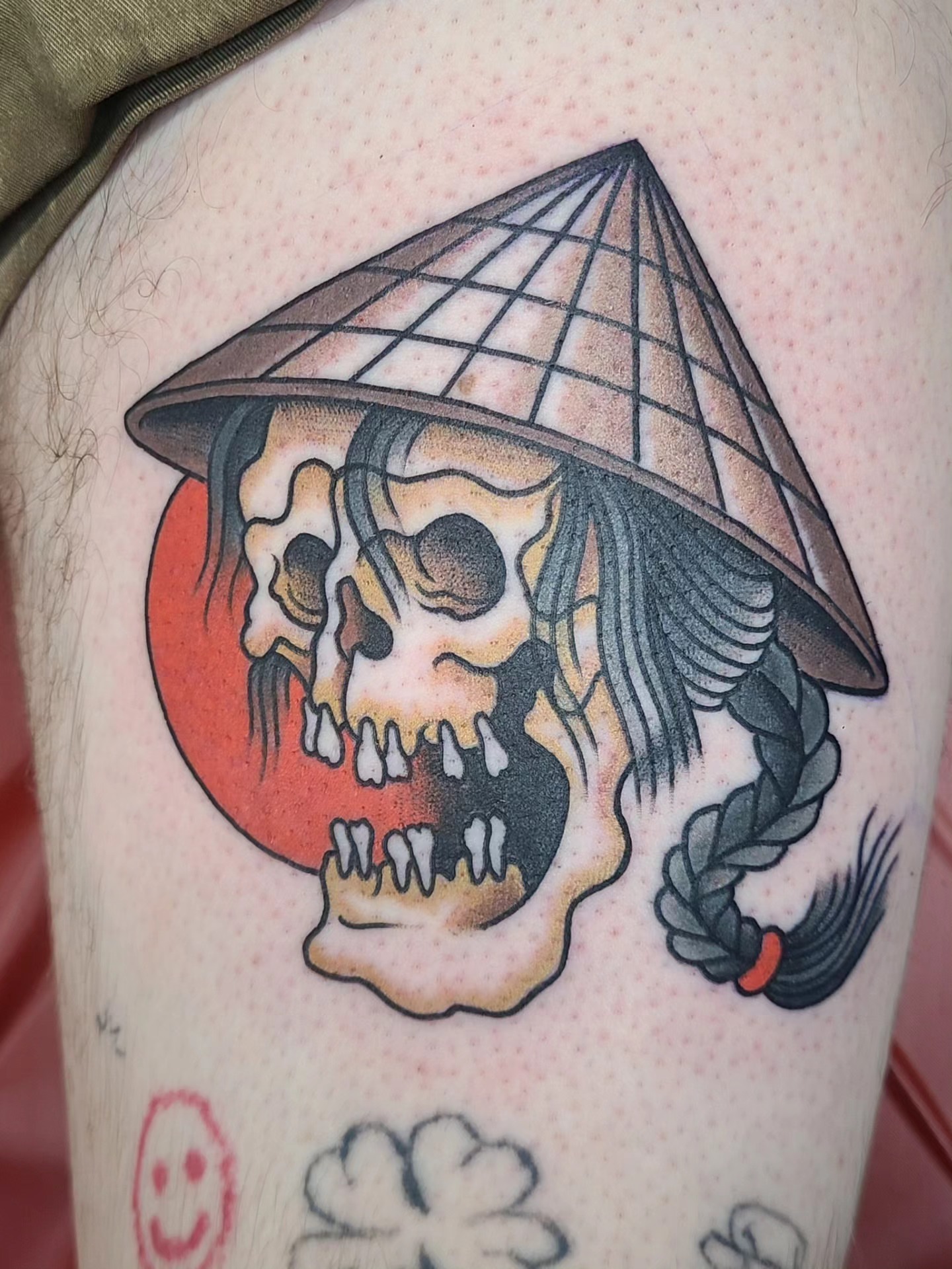 Skull wearing a conical hat American traditional tattoo on the thigh by David Vodicka