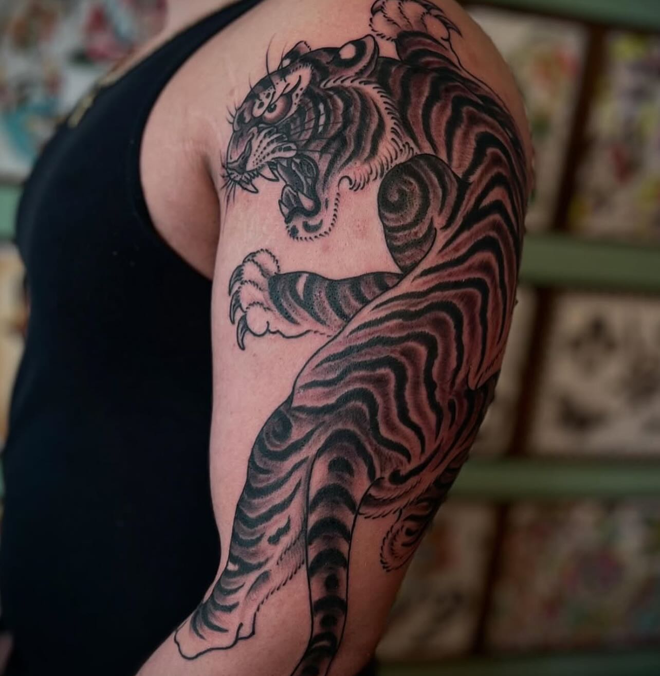 Tiger black and grey tattoo on the upper arm by Chris Romolini