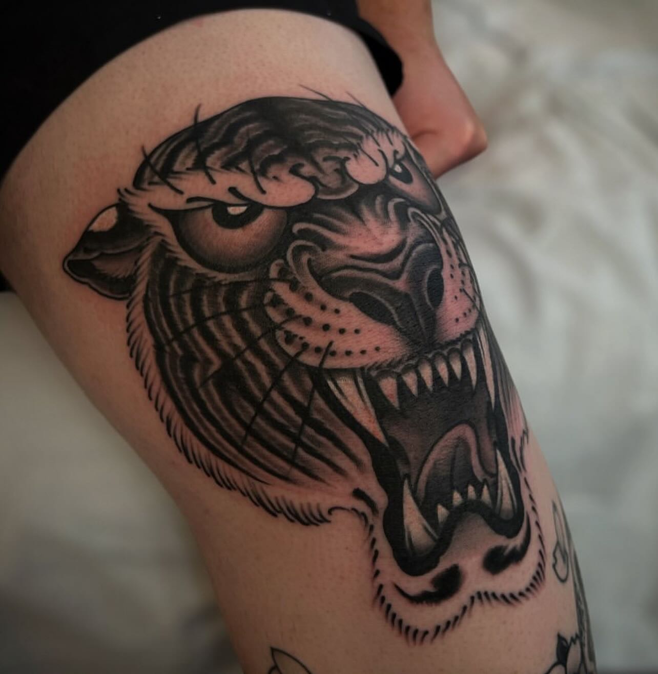 Roaring tiger American traditional tattoo on the thigh by Chris Romolini
