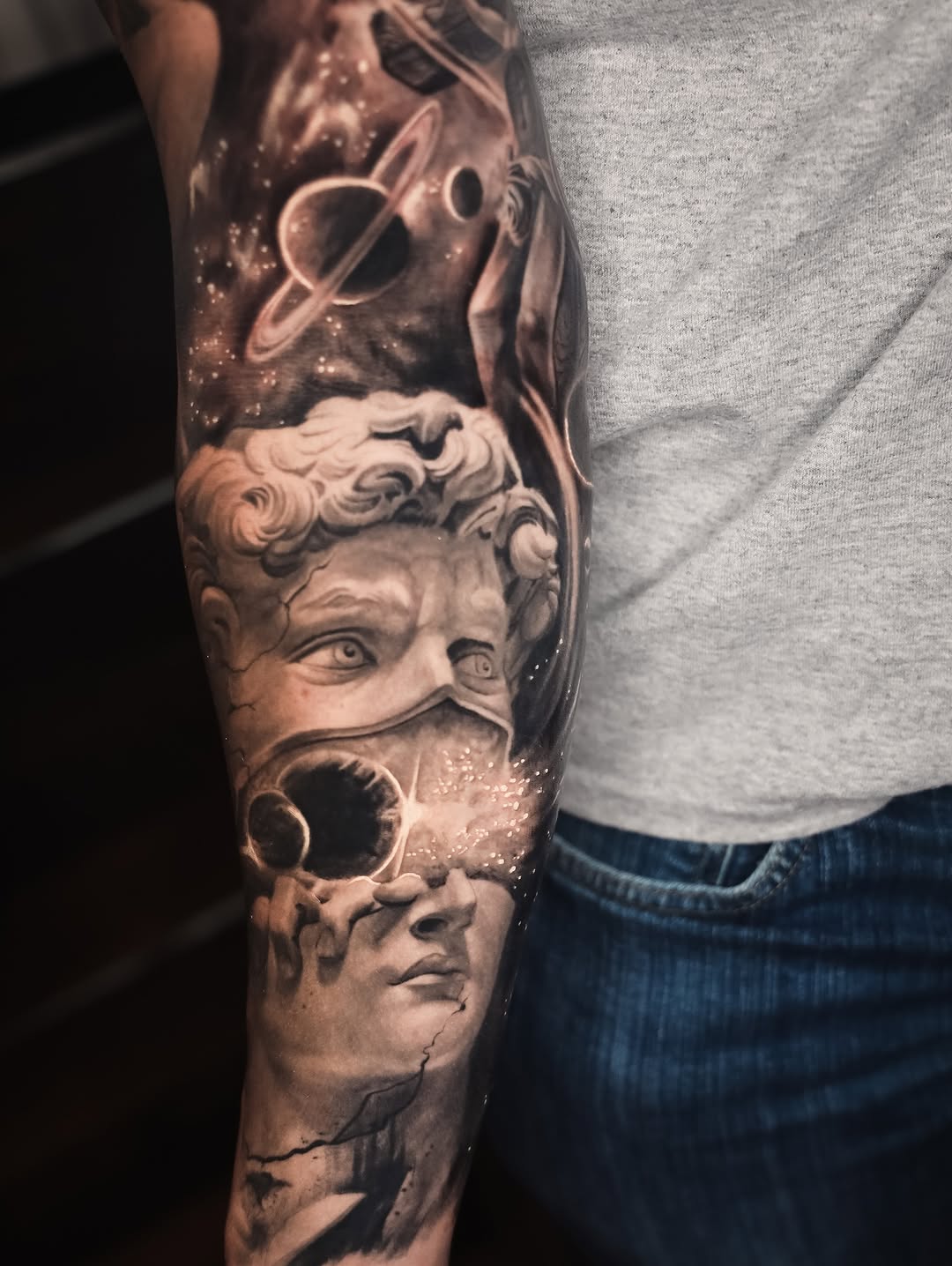 Statue head and space surrealism tattoo on the forearm by angel.antonio.tattoos
