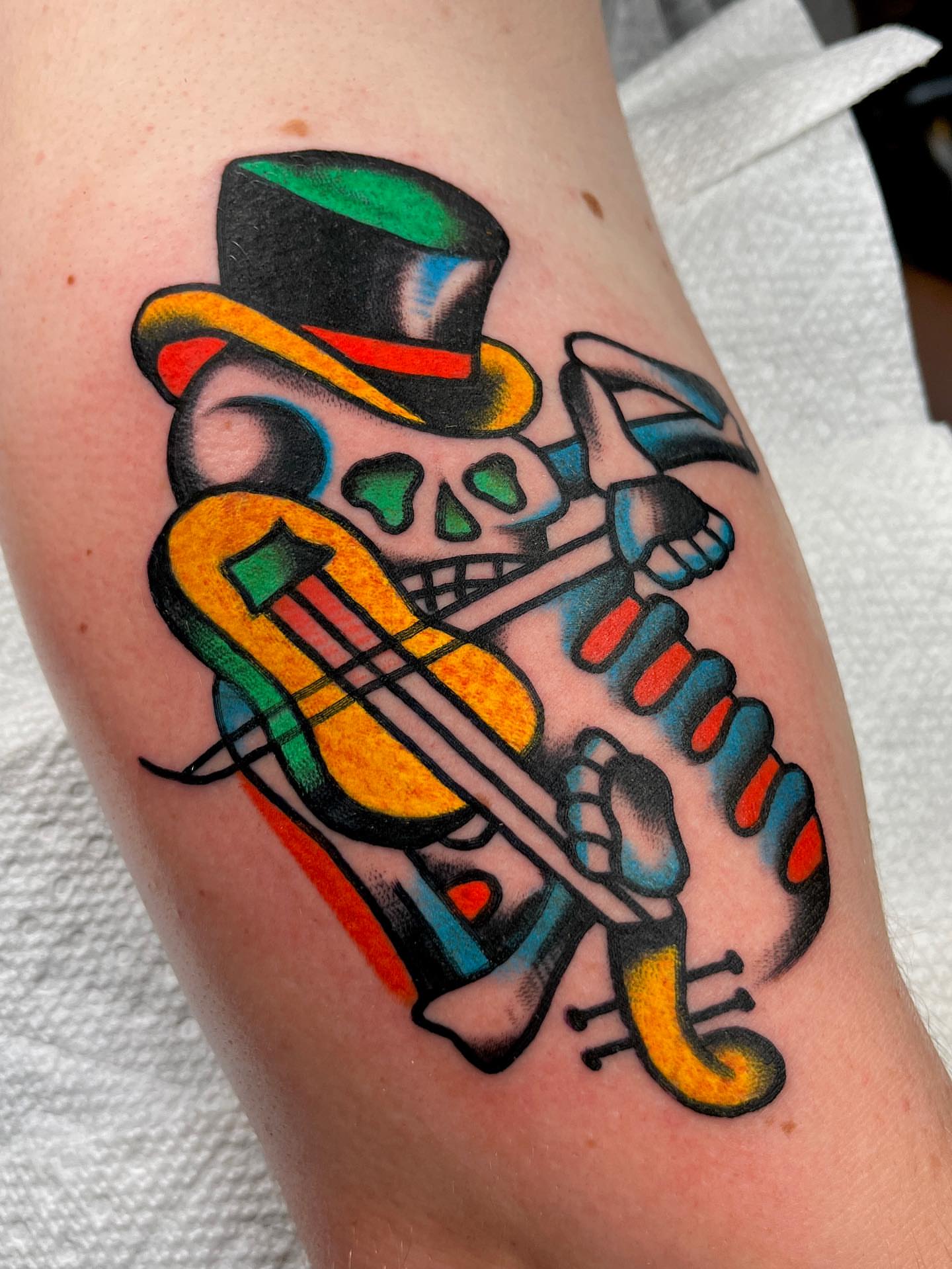Violinist skeleton American traditional tattoo on the forearm by Charlie Ostrom, Durham, North Carolina