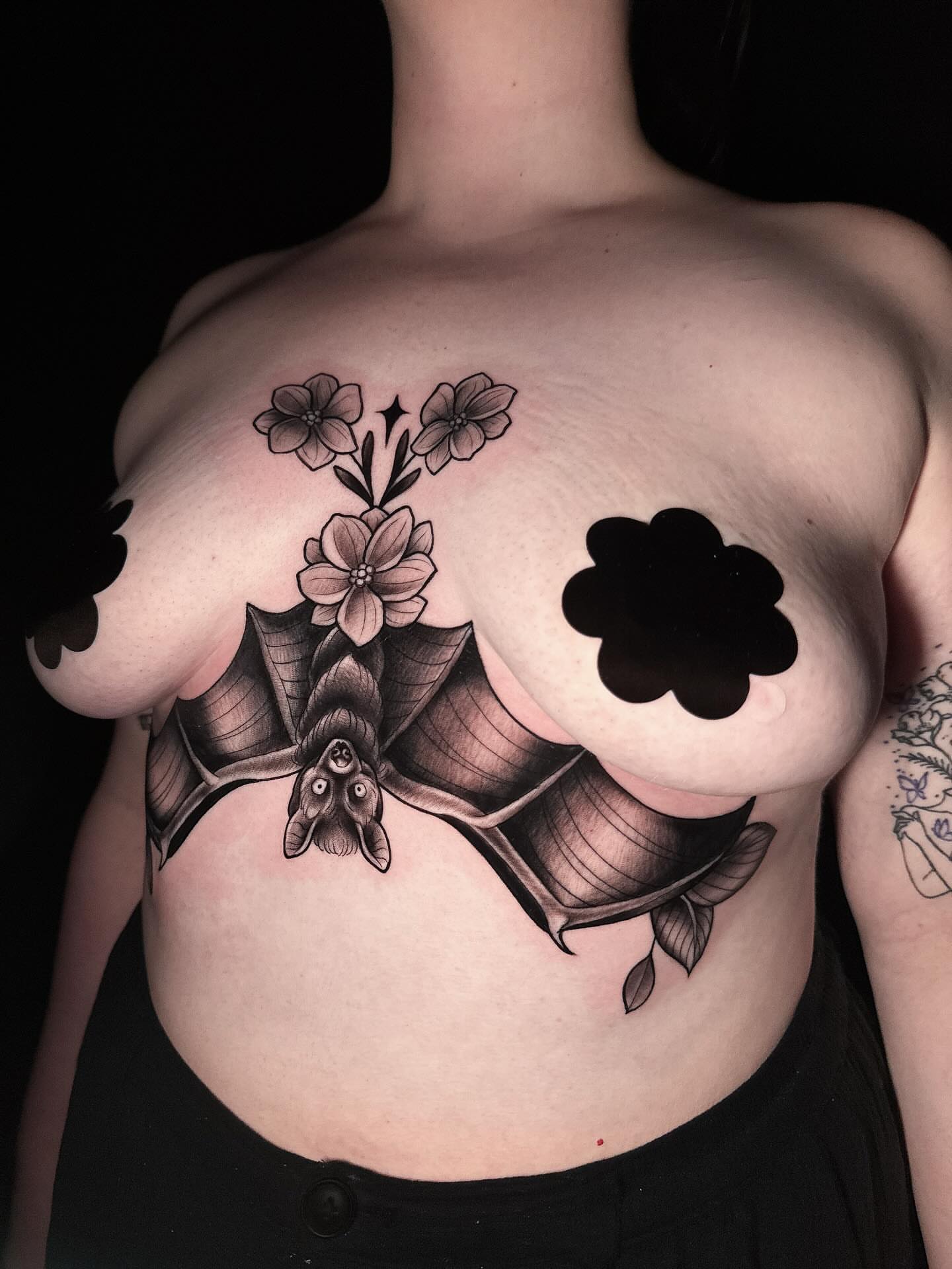 Bat and flowers black and grey tattoo on the chest by Amber