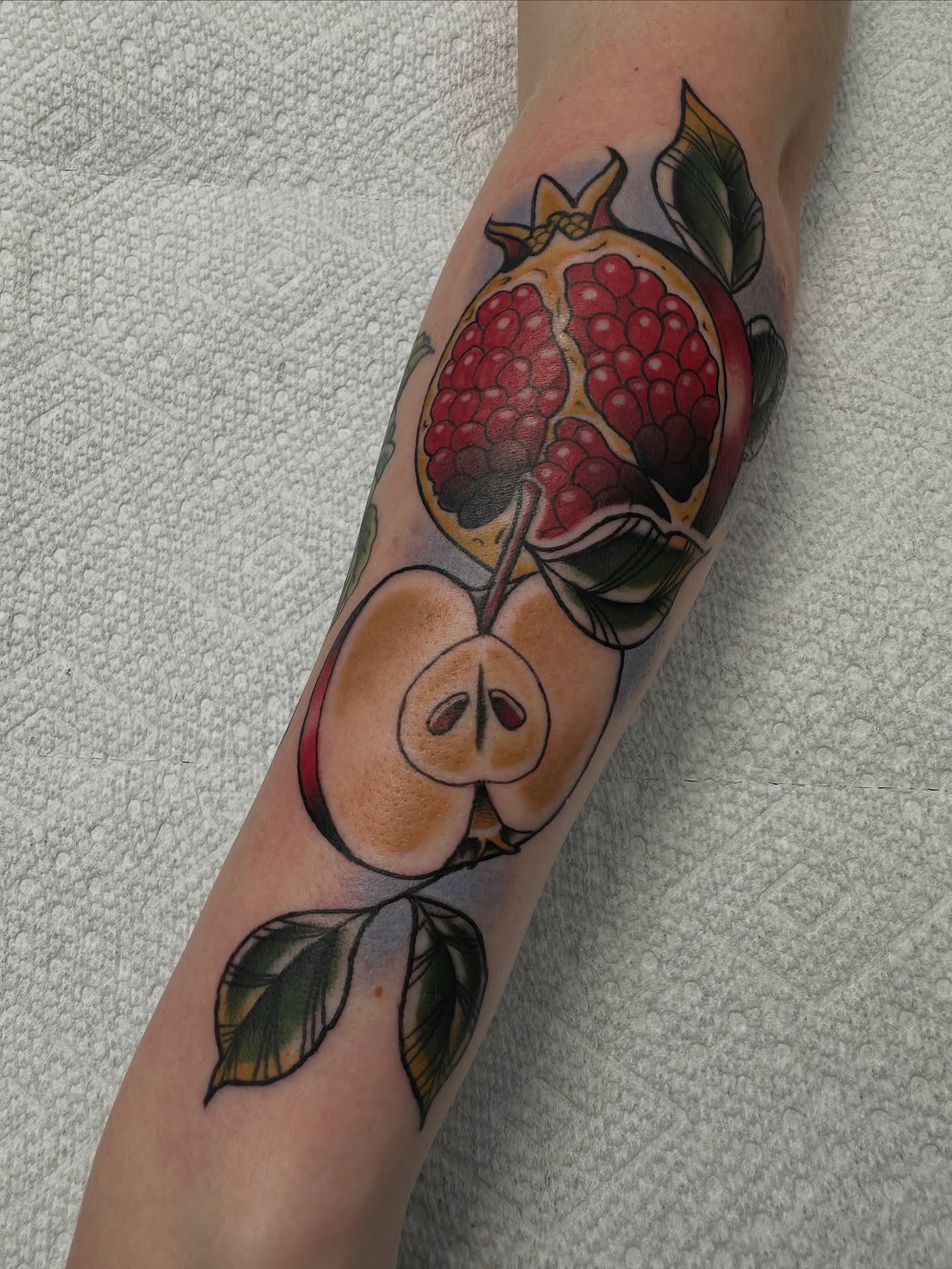 Pomegranate and apple realism tattoo on the forearm by Heather Cherish
