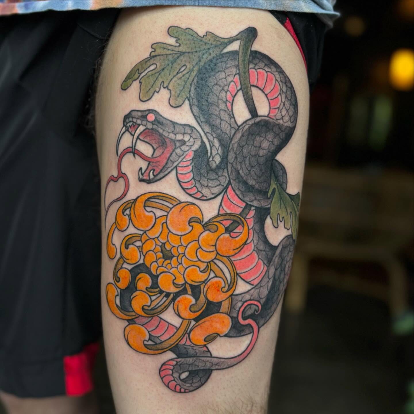 Snake and chrysanthemum American traditional tattoo on the thigh by Ian White