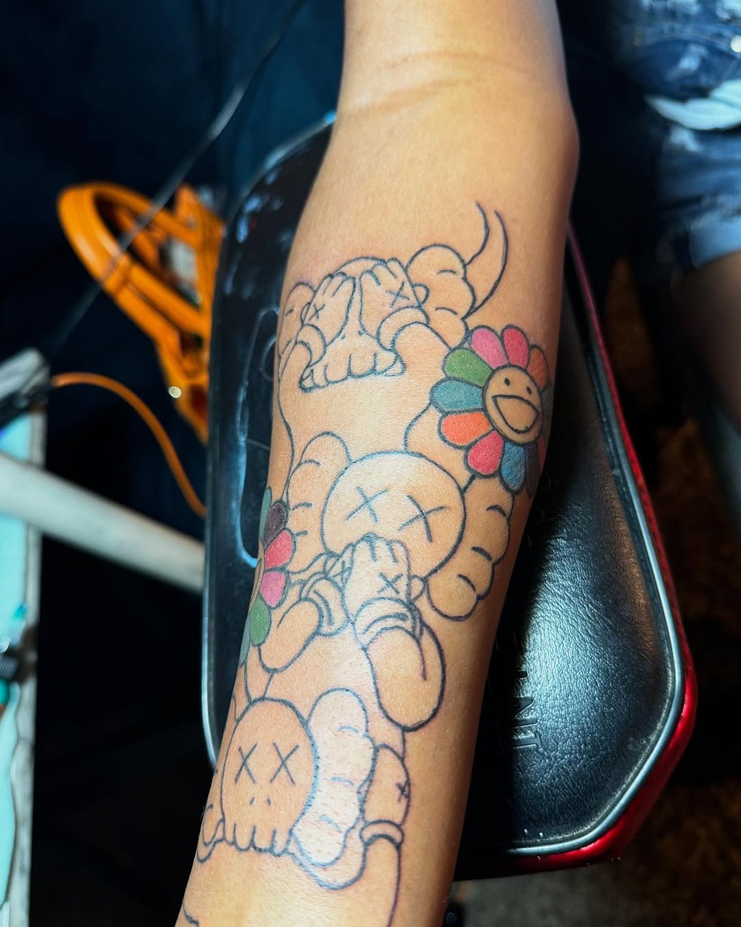 Kaws characters and Murakami flower new school tattoo on the forearm by Family and Loyalty