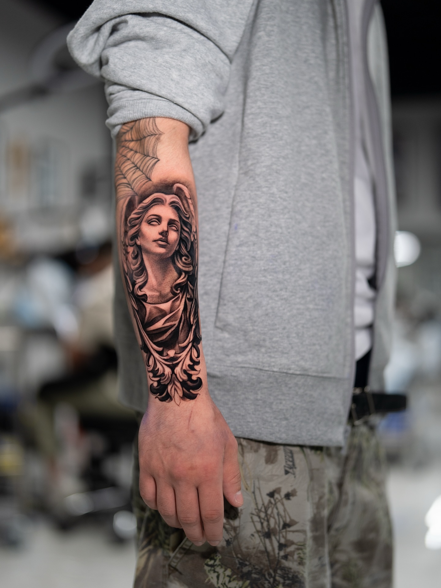 Statue head black and grey tattoo on the forearm by Joey Hella Tattoo Artist