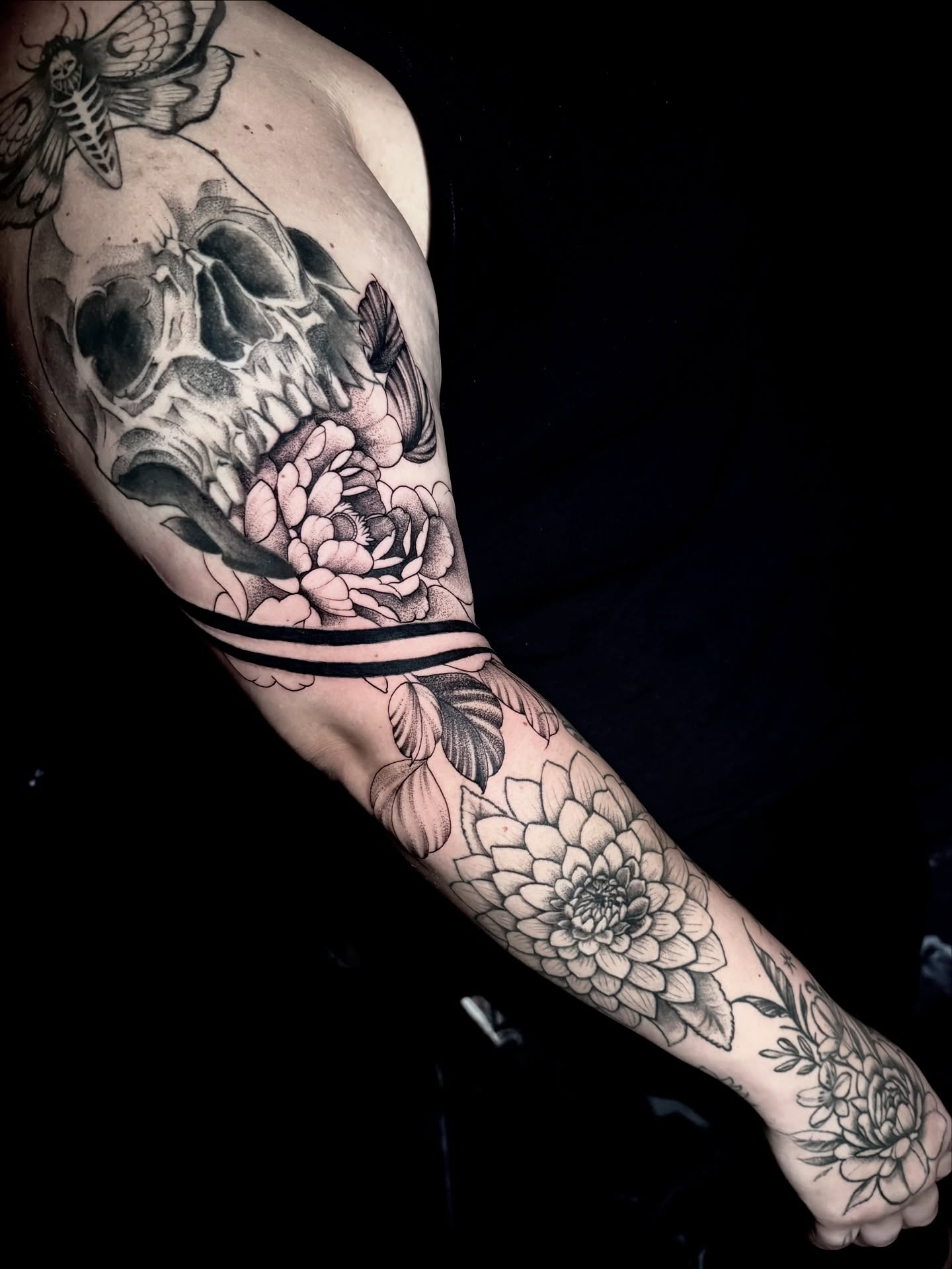 Skull and flowers realism tattoo on the forearm by Dante Singh