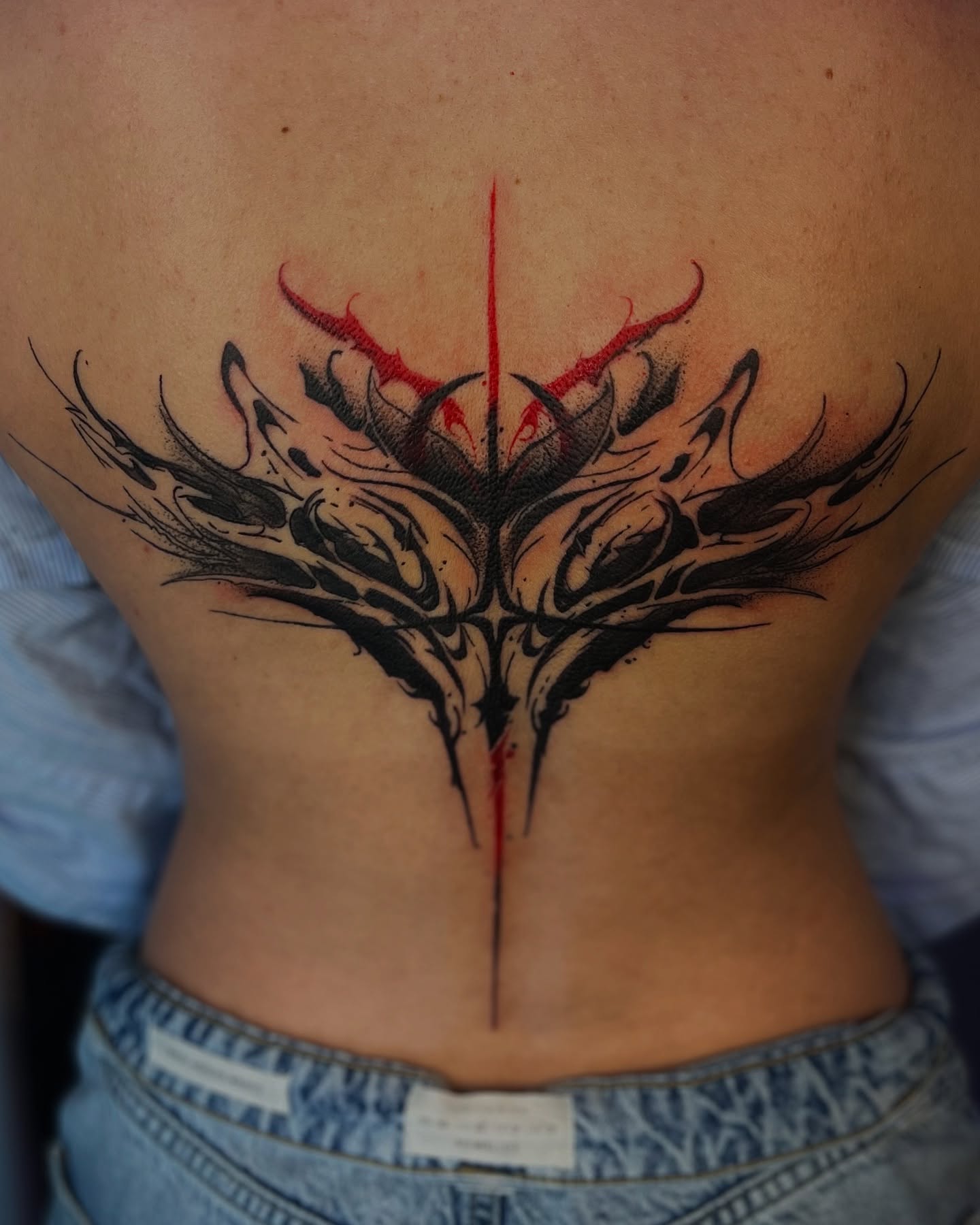Abstract design tribal tattoo on the back by Nikki Ward
