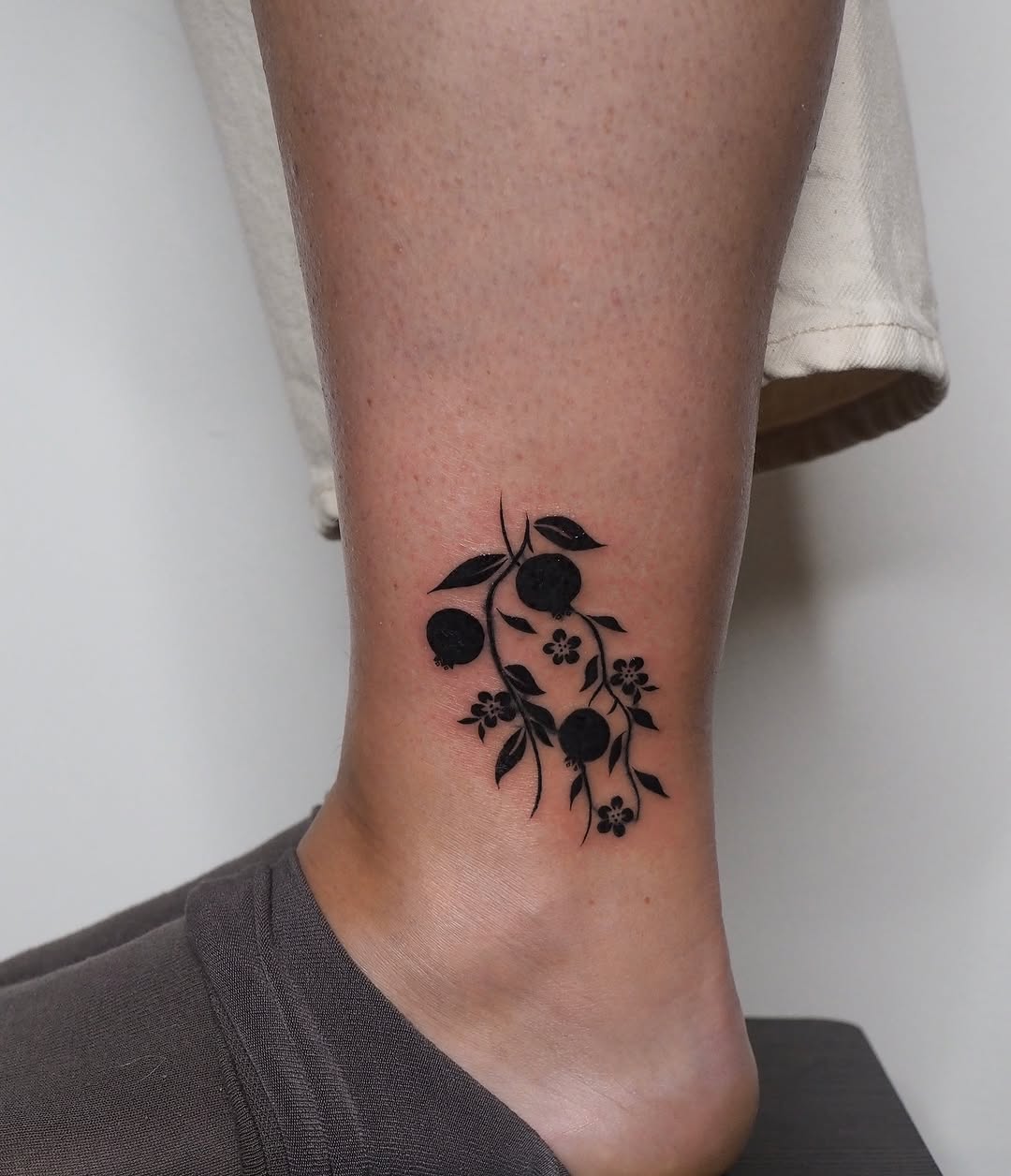 Branch with fruit and flowers ignorant tattoo on the calf by A. Eye Tat