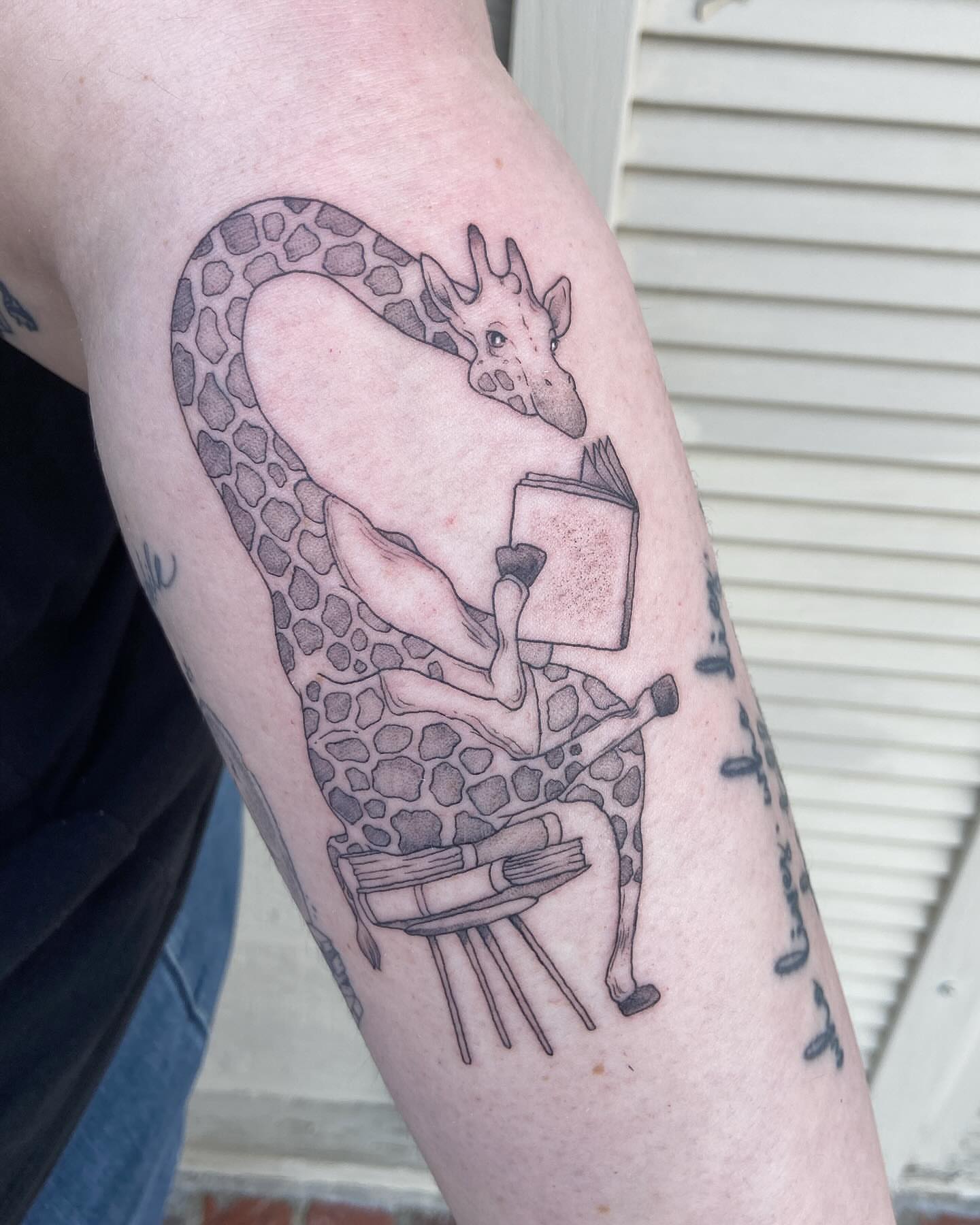 Giraffe reading book realism tattoo on the forearm by Libbey June @ Snailberry Studios- NW OHIO
