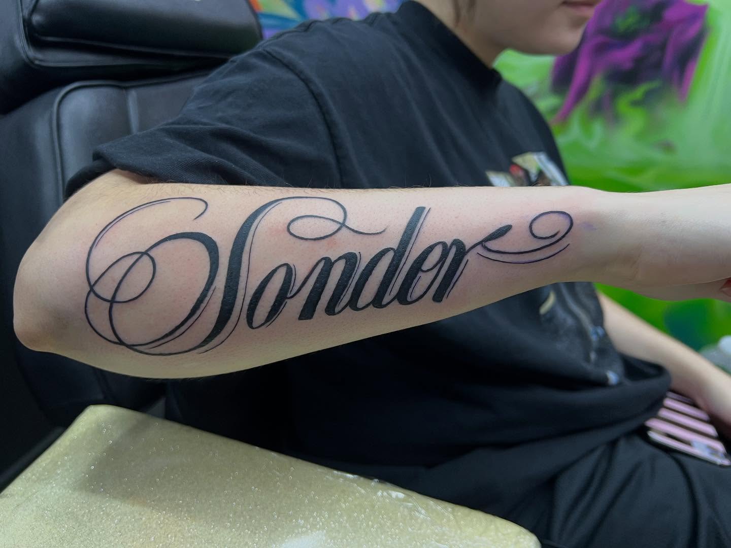 Sonder lettering script tattoo on the forearm by Sav