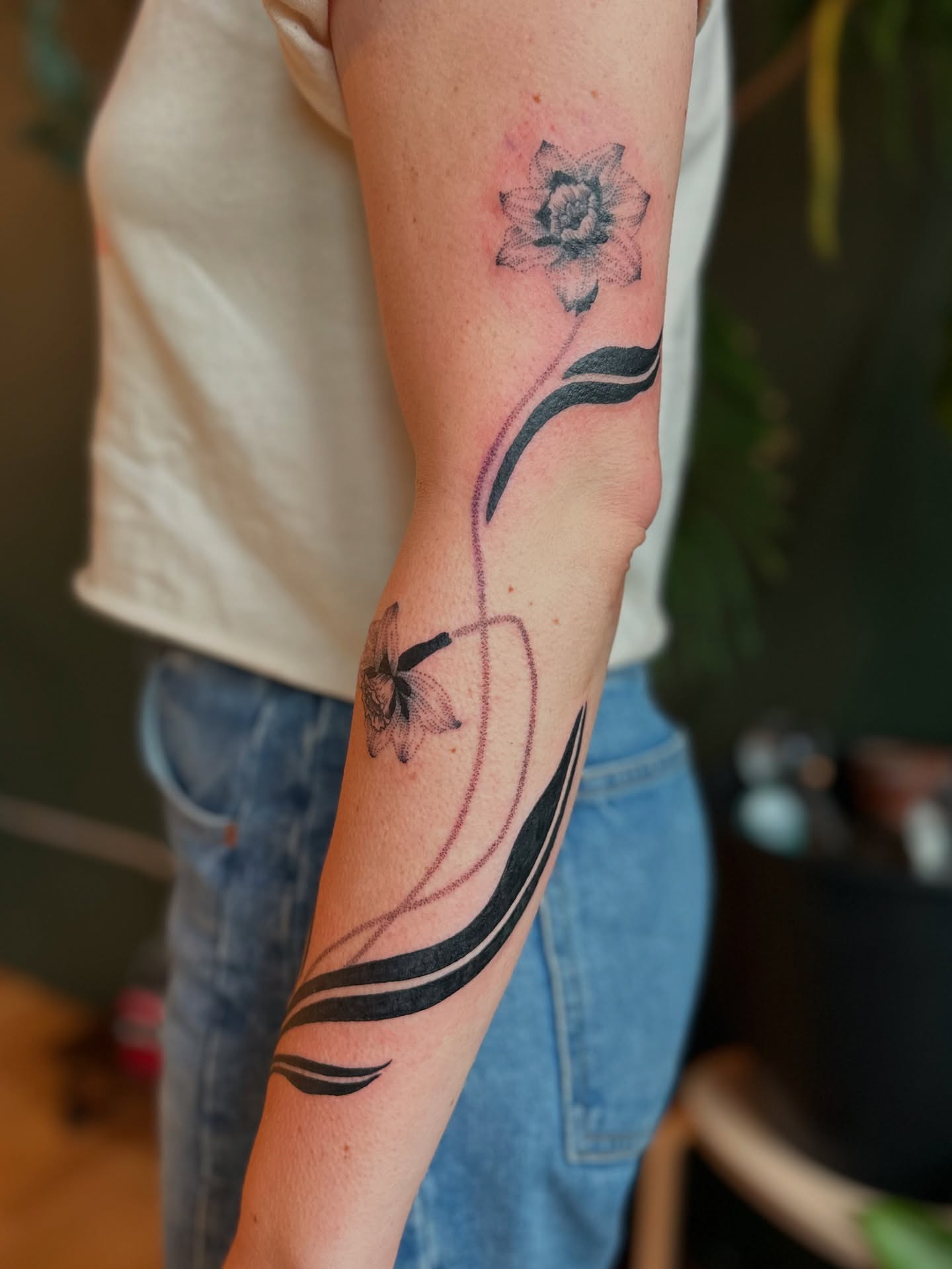 Daffodil and butterfly black and grey tattoo on the forearm by Alexandra Gray