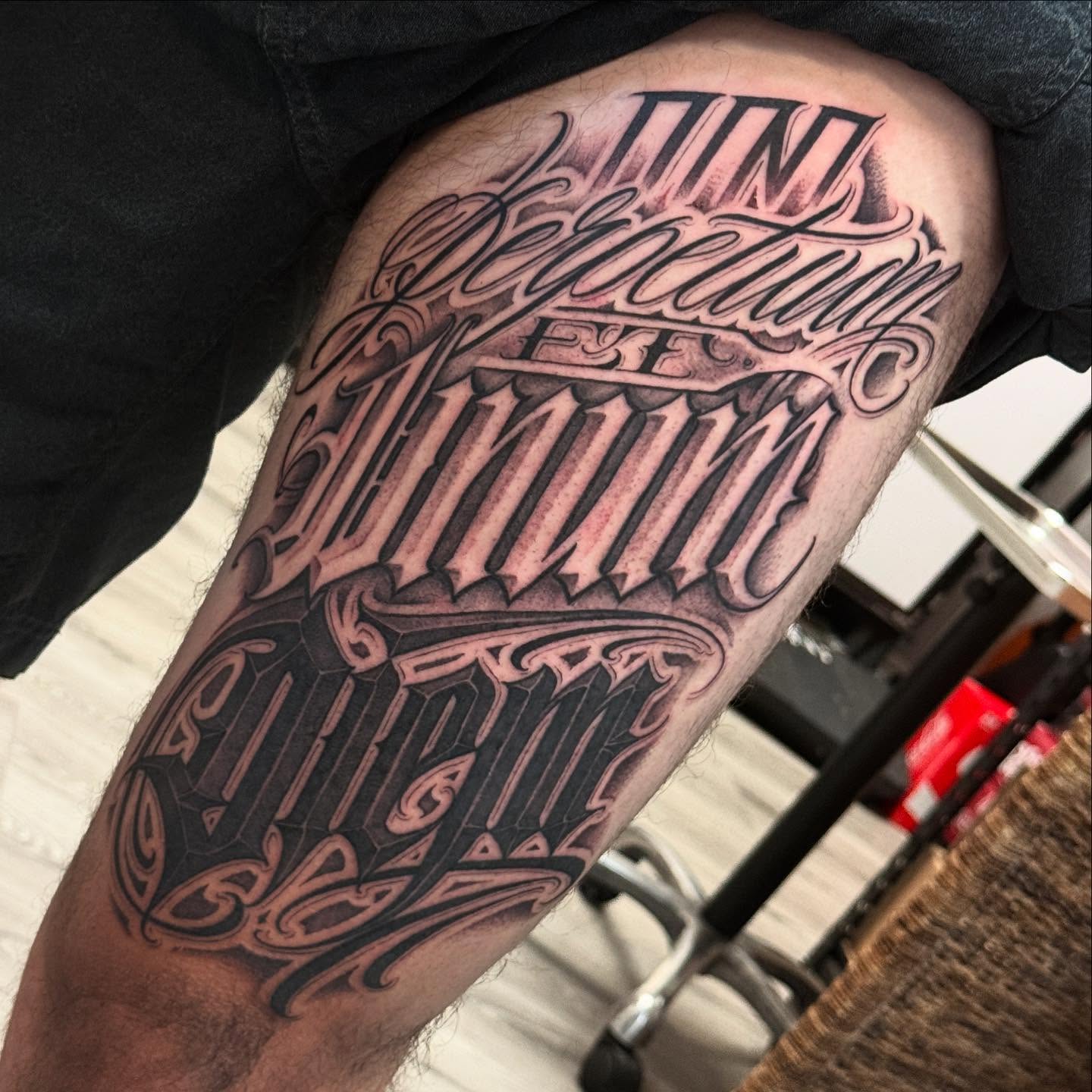Latin phrase lettering script tattoo on the thigh by Chicanocustomlettering
