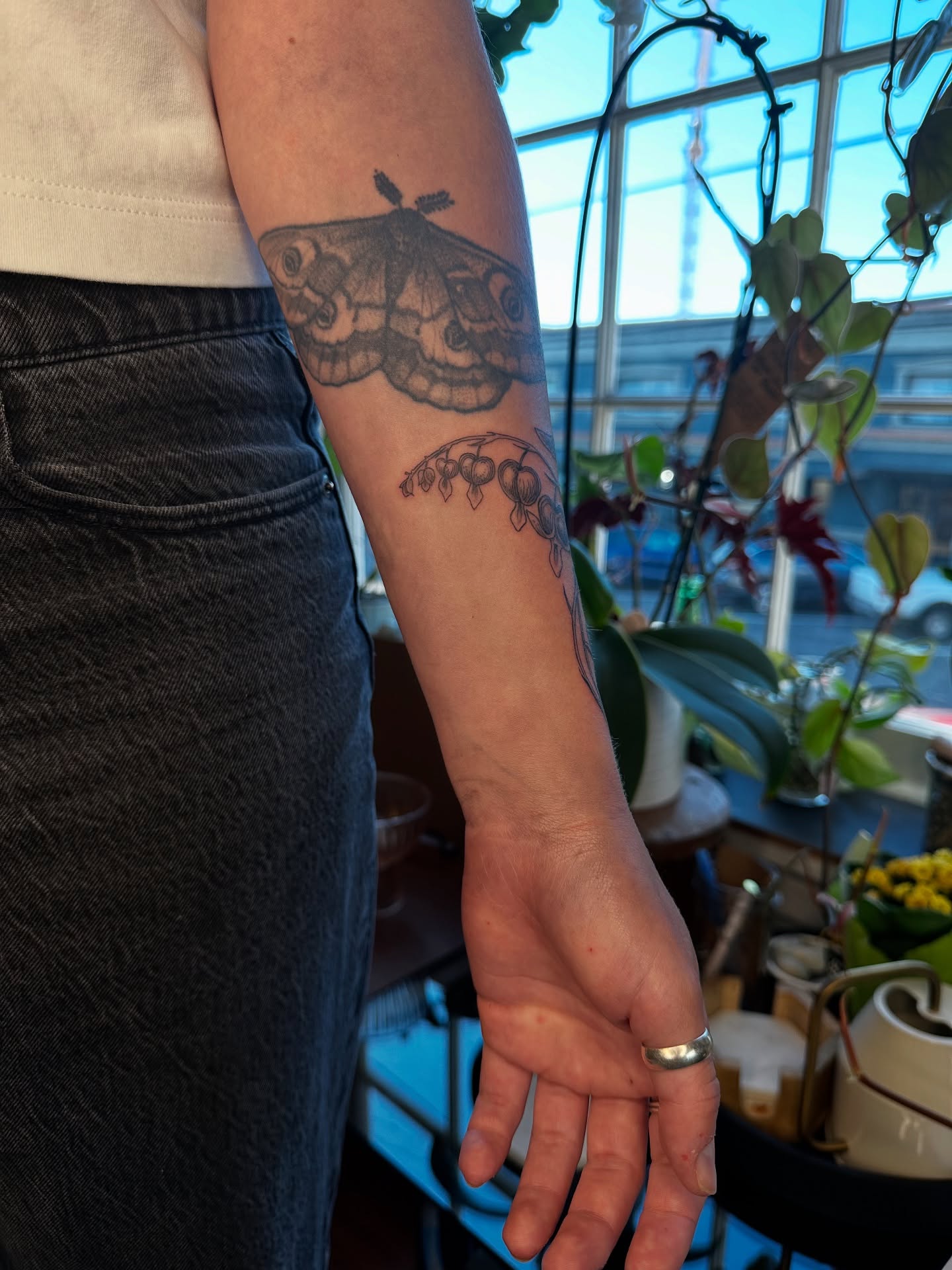Moth and berries black and grey tattoo on the forearm by Emma Thompson