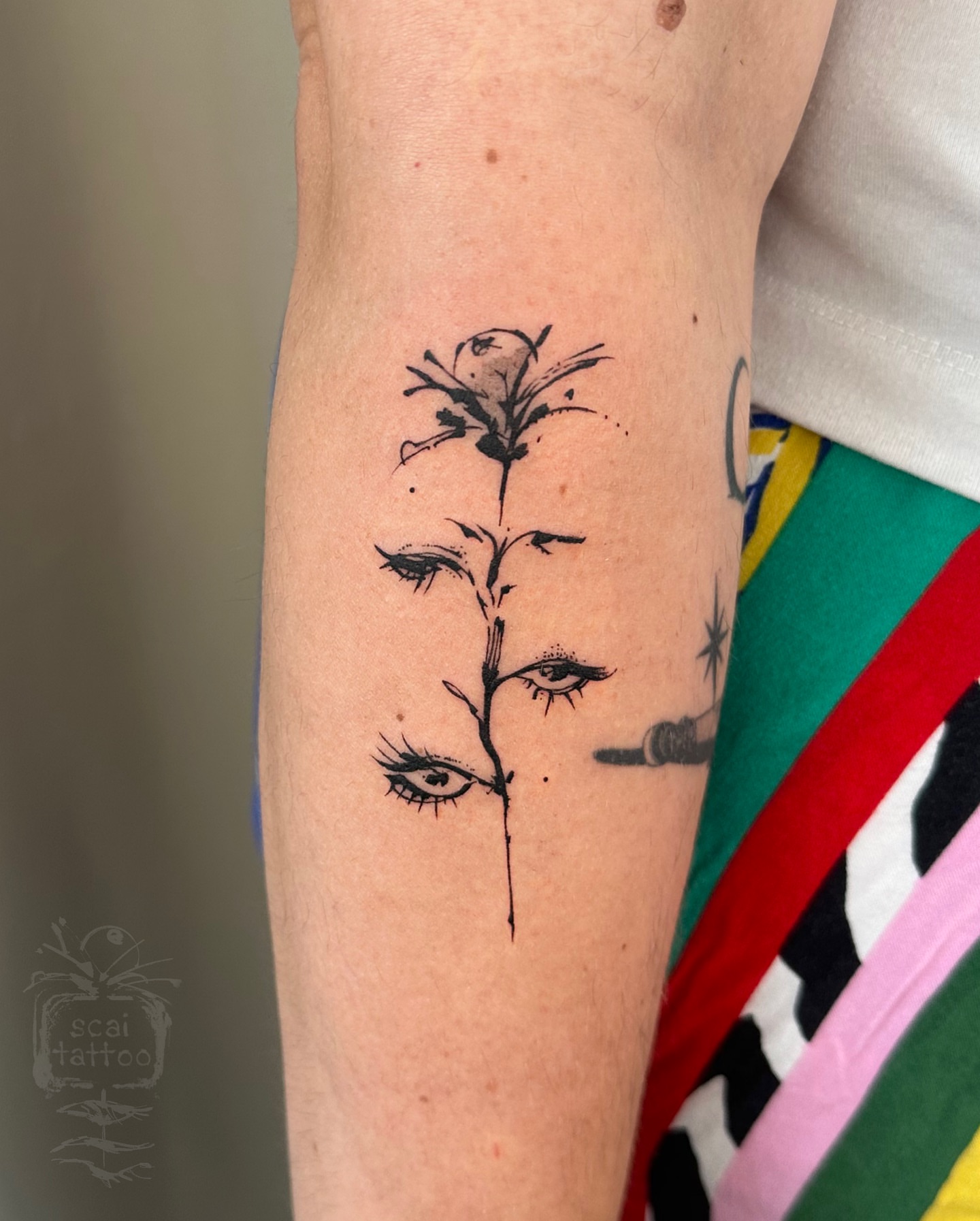 Flower with eyes black and grey tattoo on the forearm by scaitattoo