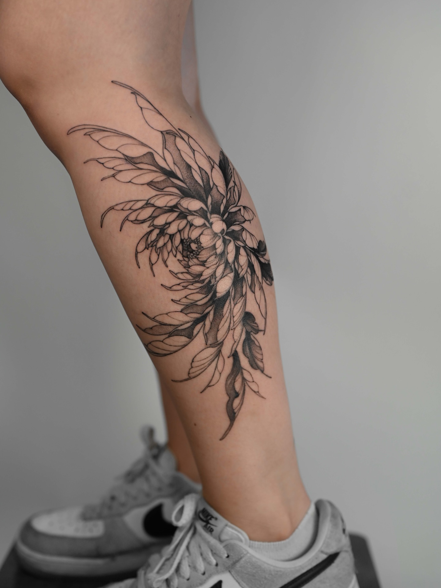 Floral arrangement black and grey tattoo on the calf by Anastasiia