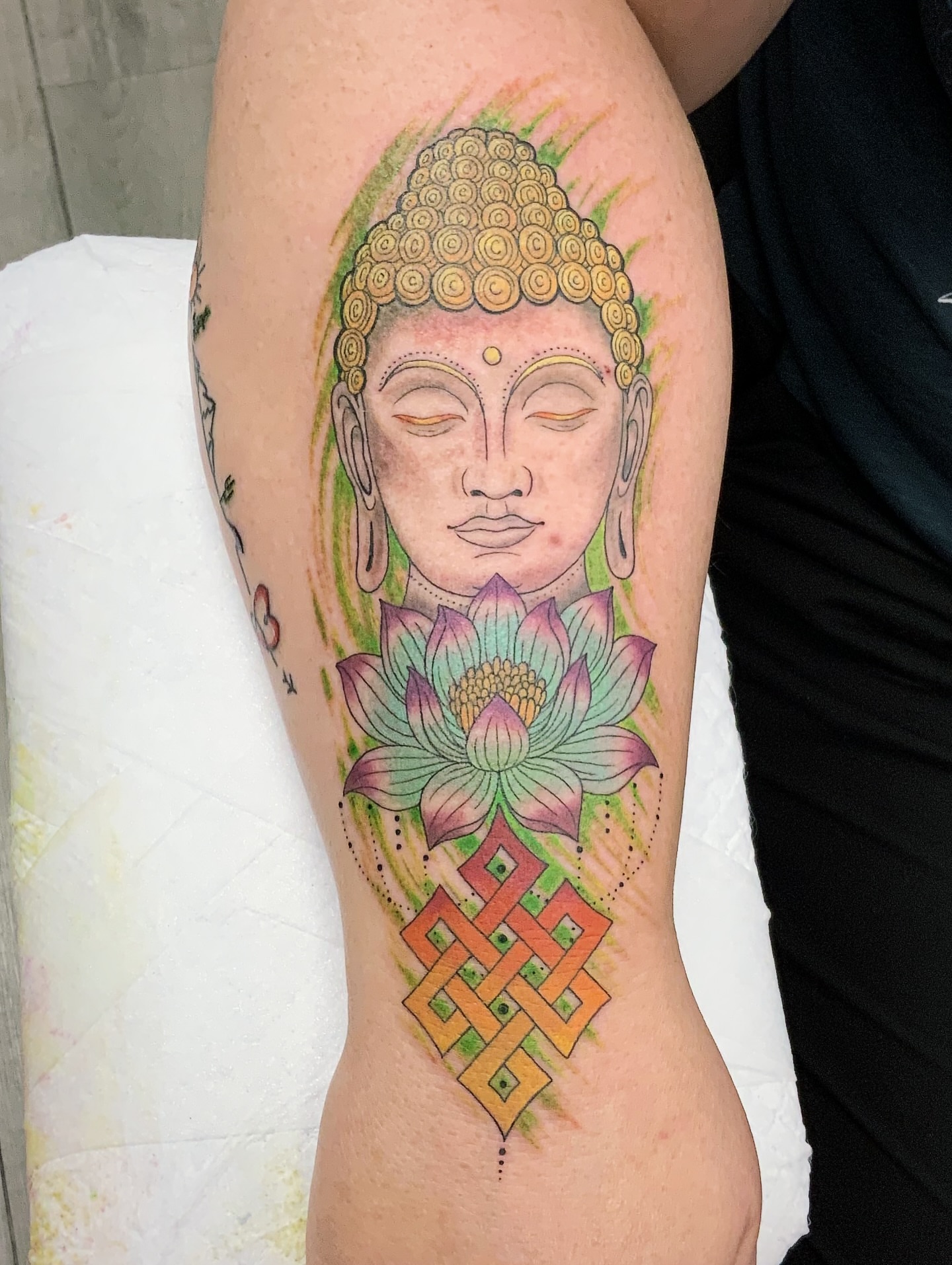 Buddha head with lotus flower watercolor tattoo on the forearm by QUEEN TATTOO Stephanie Larson