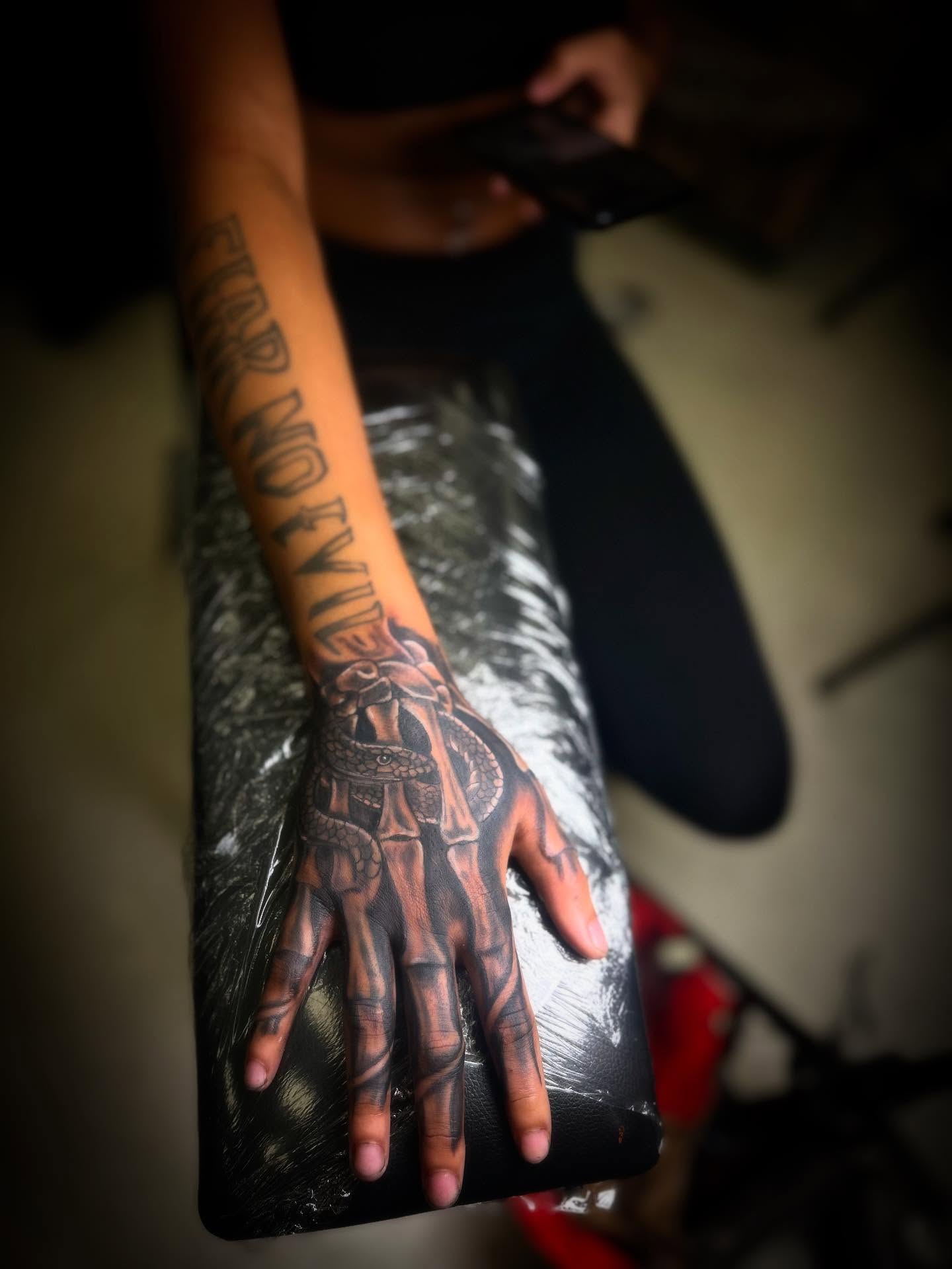 Hand with snake realism tattoo on the forearm by Rell Washington, Marlow Heights, Maryland