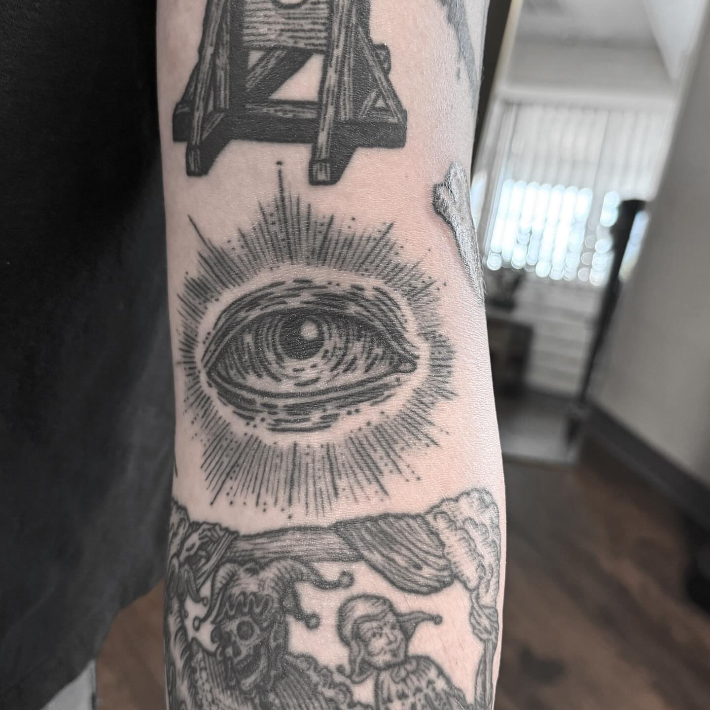 Eye with radiating lines black and grey tattoo on the forearm by Joe Truck