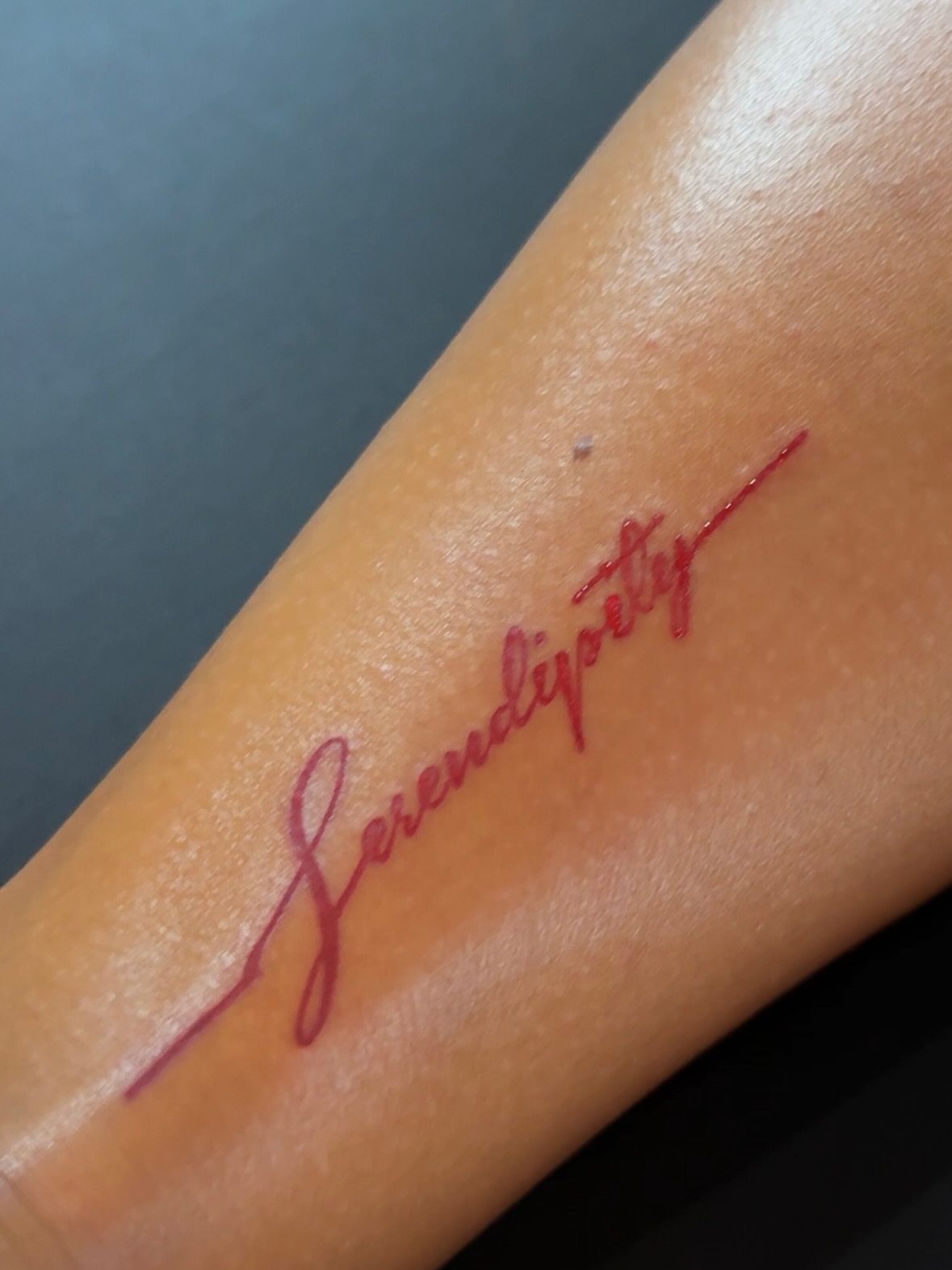 Serendipity lettering script tattoo on the forearm by @blackastaratattoo