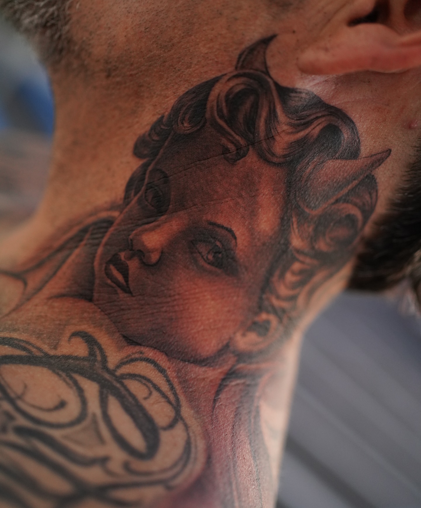 Woman's face realism tattoo on the neck by tombstone