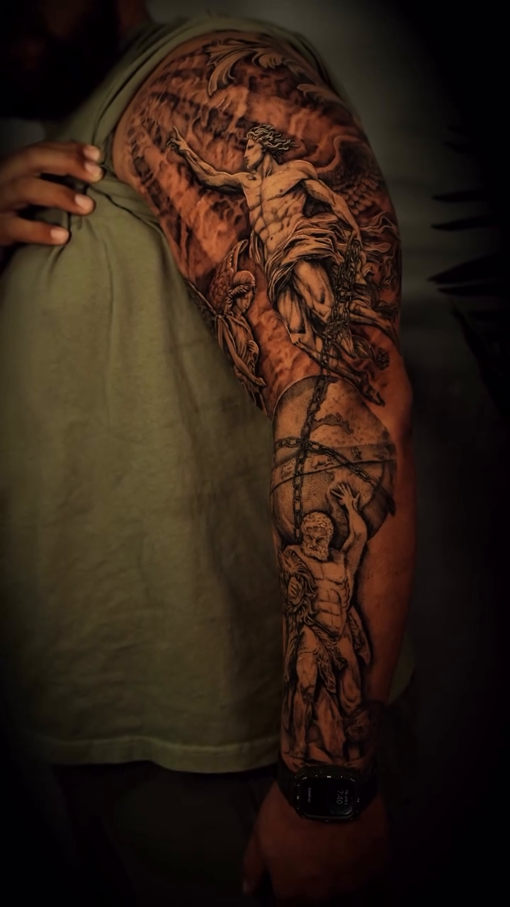 Religious figures and a portrait realism tattoo on the upper arm by Nyc Tattoo Manhattan