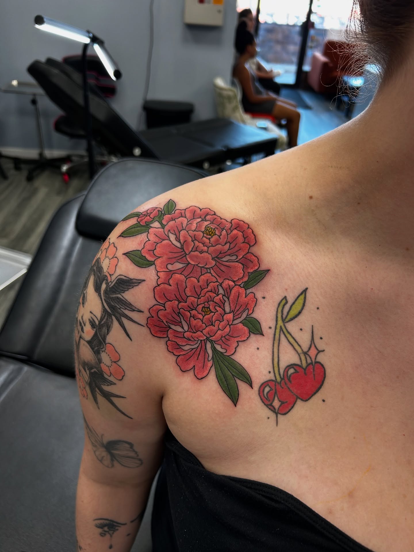 Peonies and cherries American traditional tattoo on the shoulder by Brittany Brutal