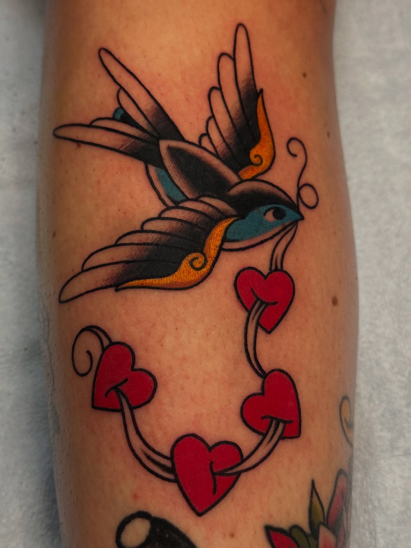 Swallow and hearts American traditional tattoo on the forearm by Emily Masa