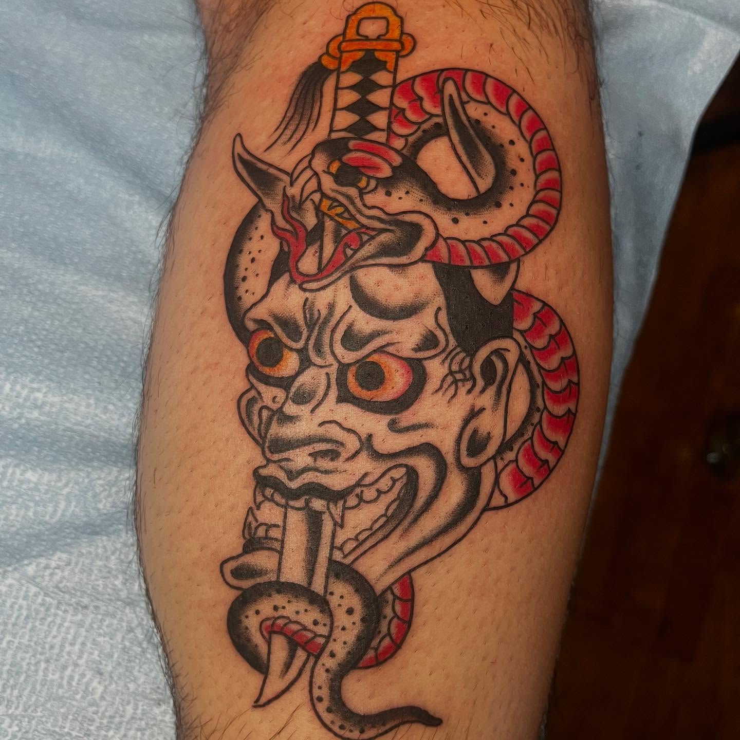 Demon mask with snake American traditional tattoo on the forearm by Mariah Nguyen