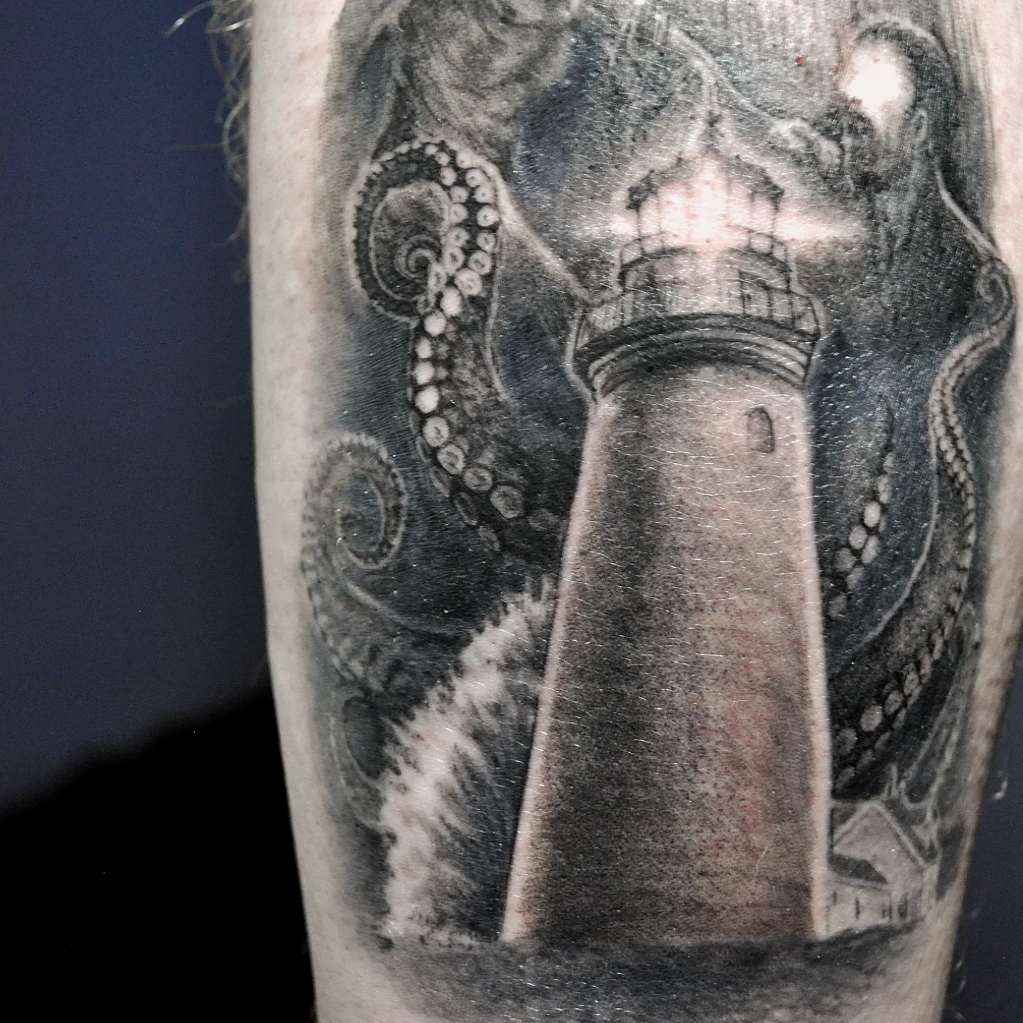 Lighthouse and octopus realism tattoo on the forearm by Bek Artz