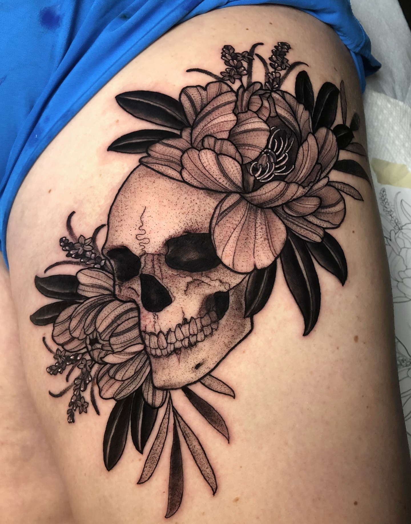 Skull and flowers realism tattoo on the thigh by Melissa Brown