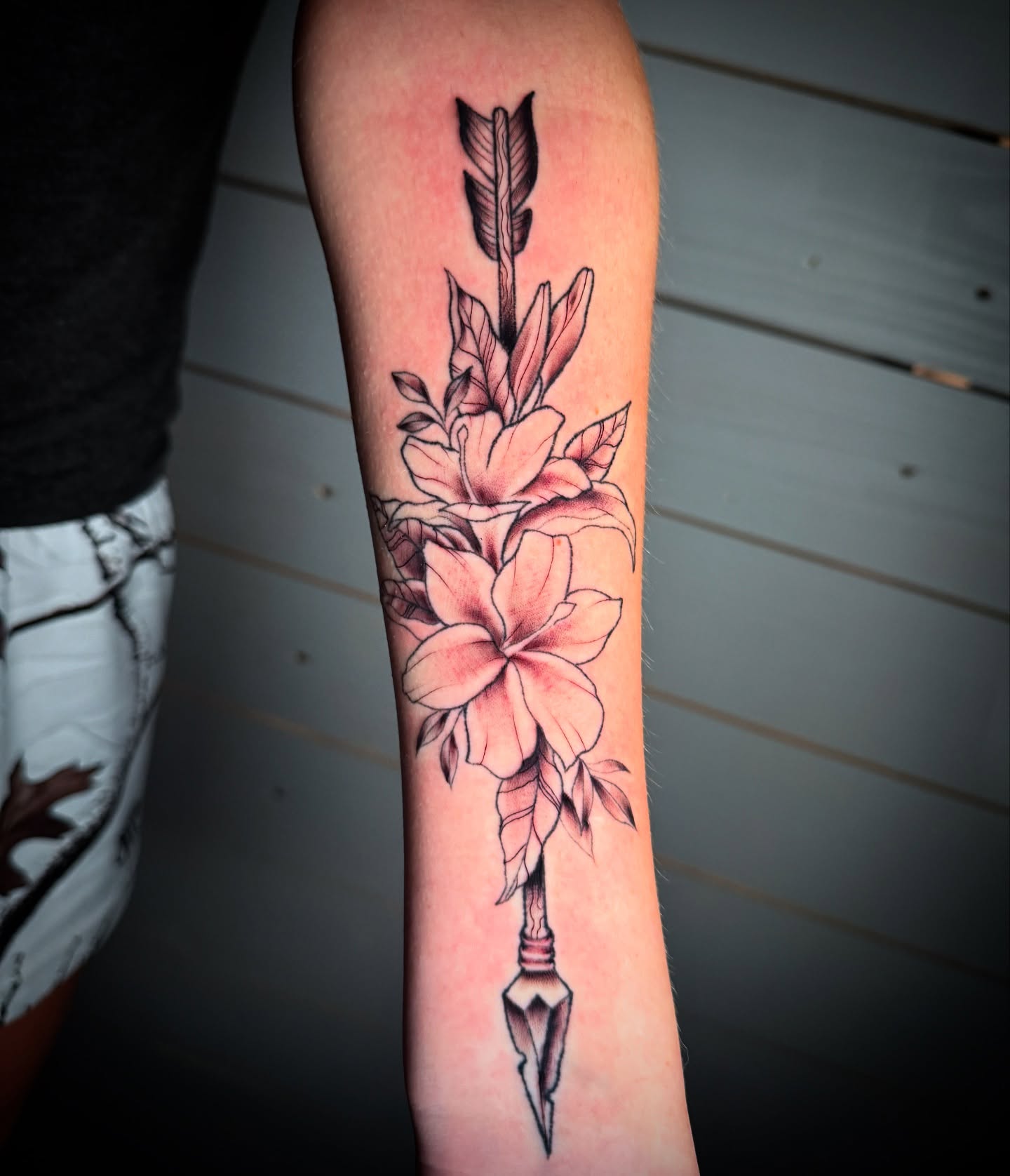 Arrow with flowers black and grey tattoo on the forearm by Tattoo & Body Artist, Gastonia, North Carolina