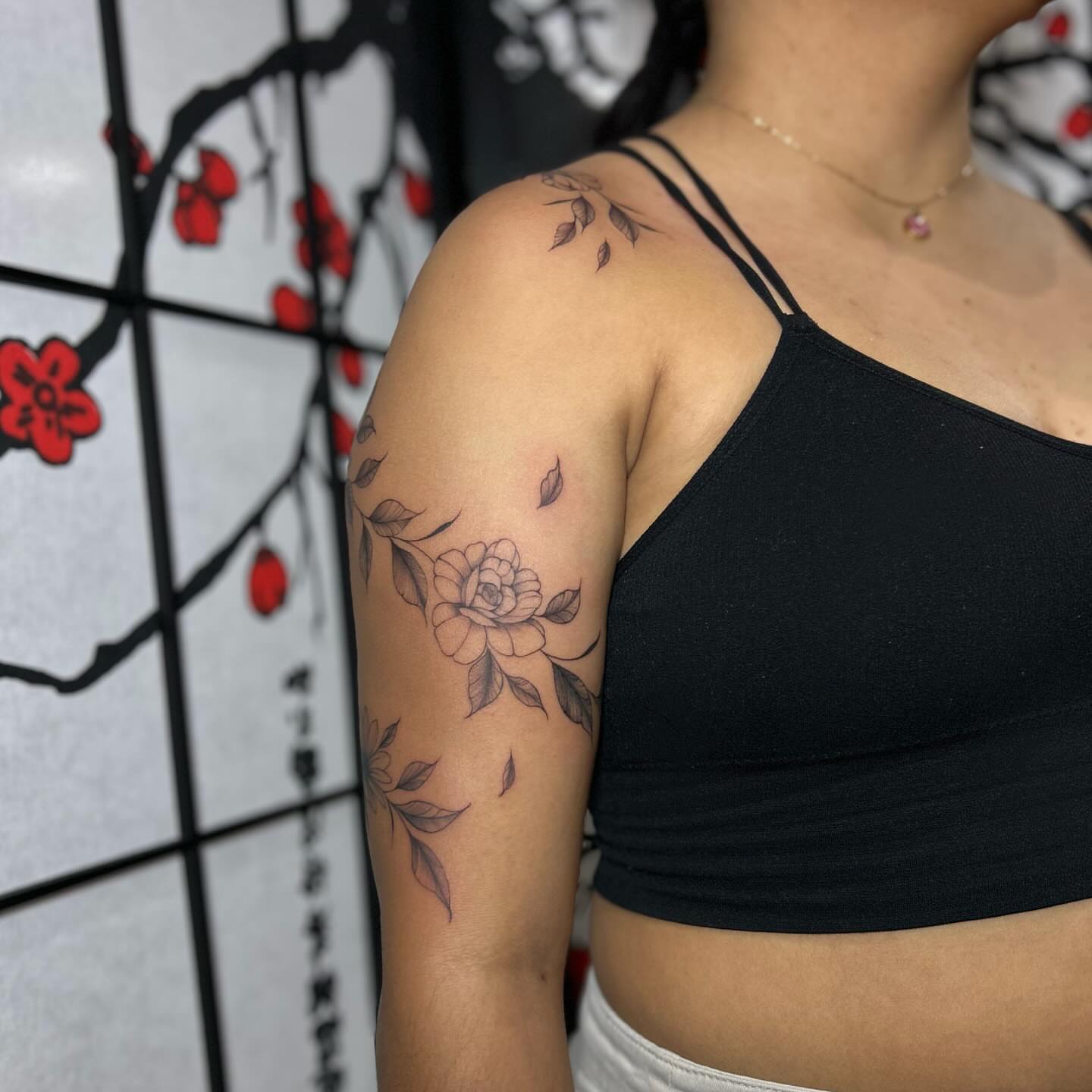Flower black and grey tattoo on the upper arm by Chloe
