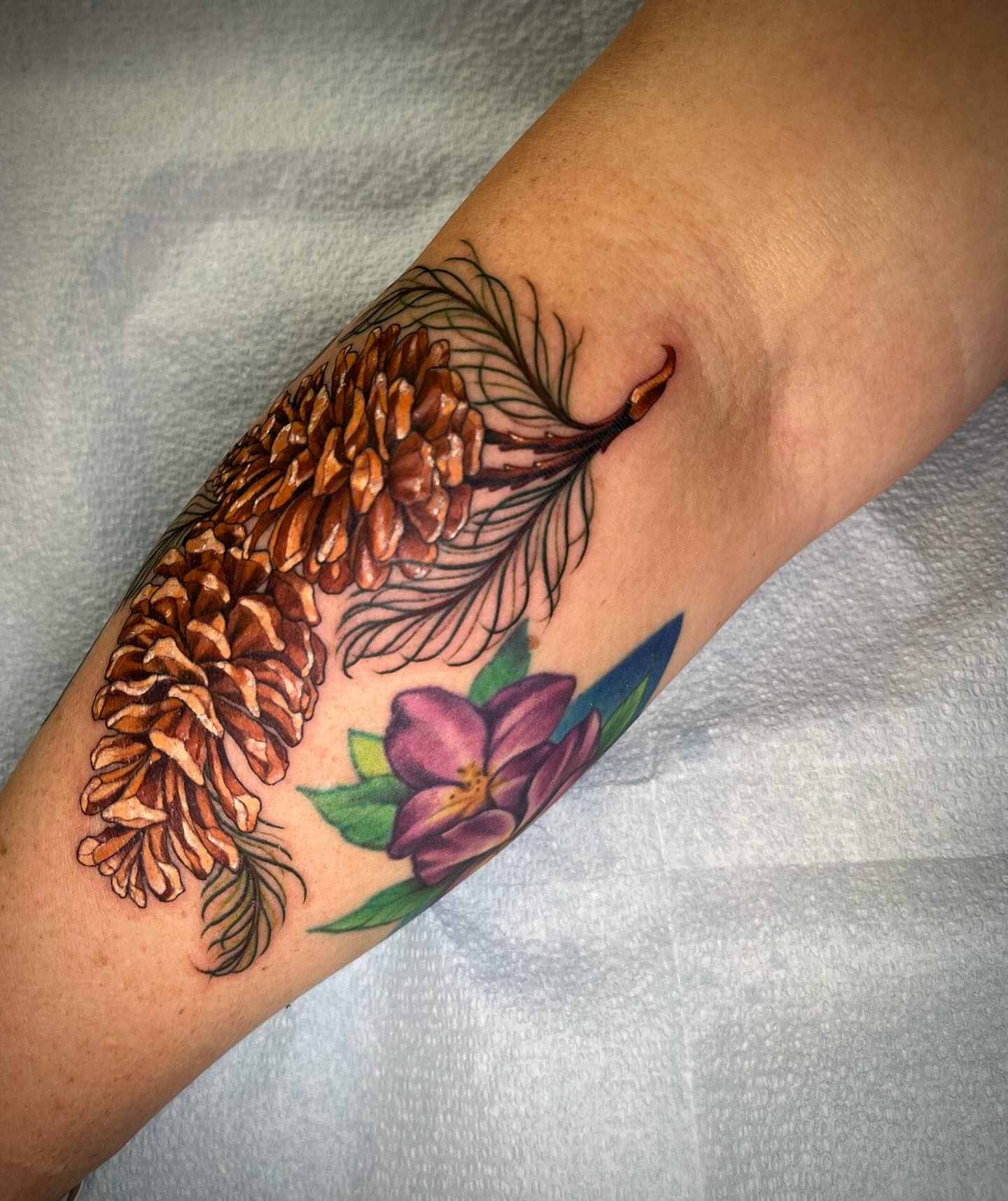 Pine cones and flower realism tattoo on the forearm by Martha Gual π€ East ATX Tattooer