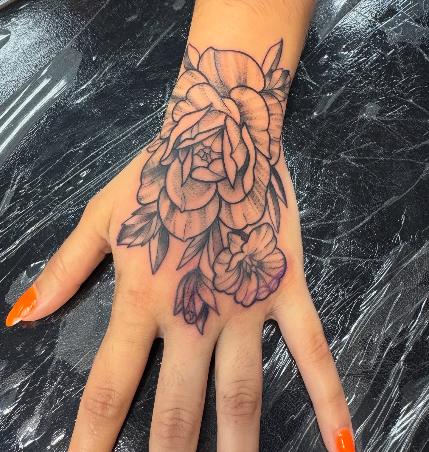 Floral arrangement black and grey tattoo on the hand by Erin Moore