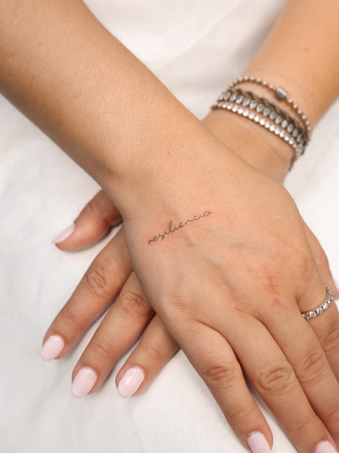 Resiliencia lettering script tattoo on the hand by Fine Line, New York, New York