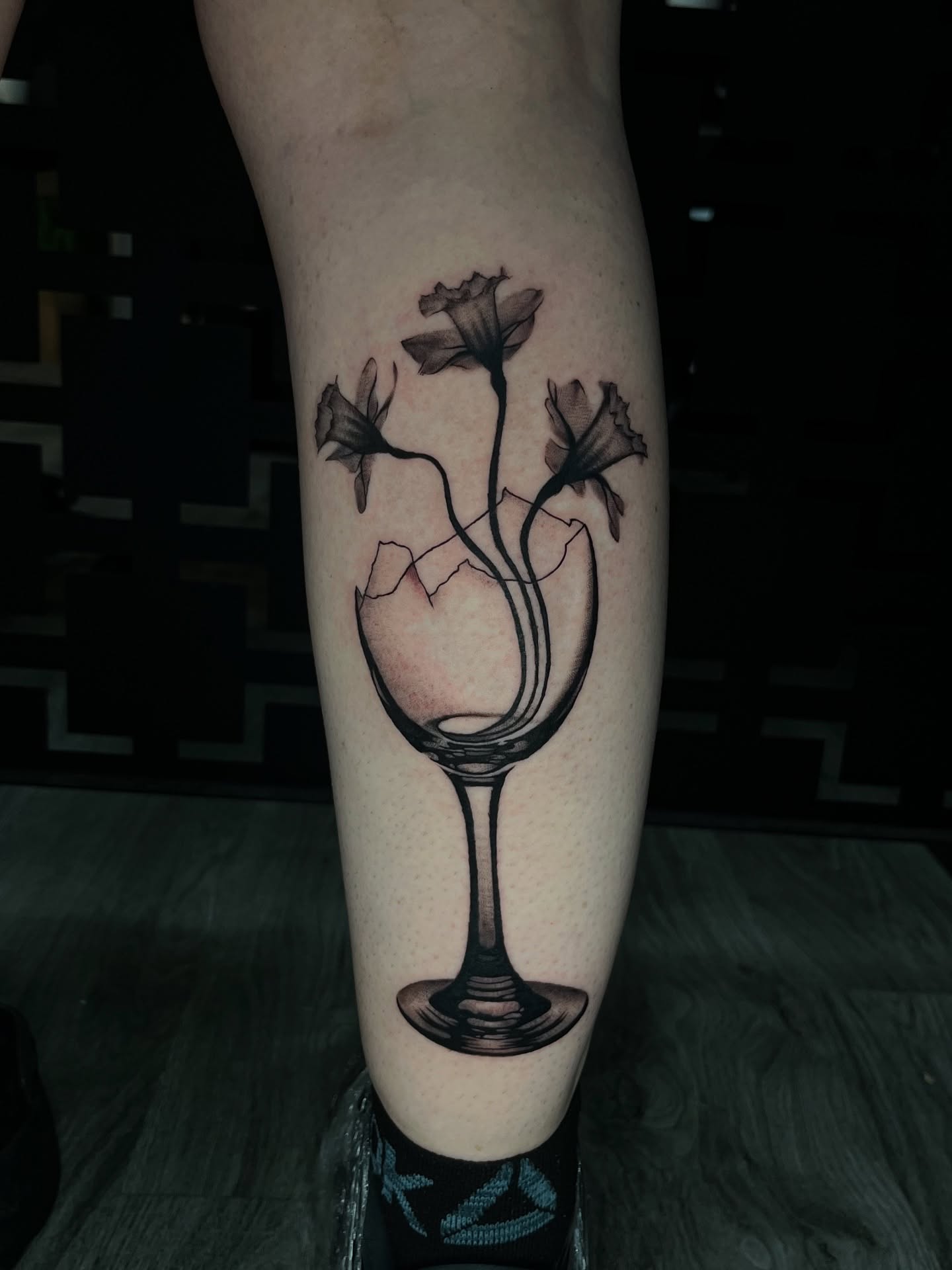 Wine glass with flowers black and grey tattoo on the forearm by Connor Arvay