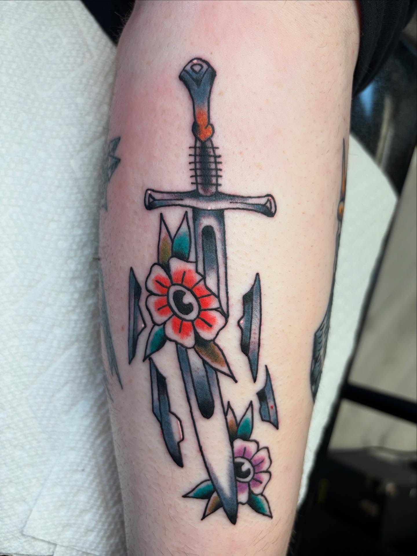Sword and flowers American traditional tattoo on the forearm by Ben Whyte