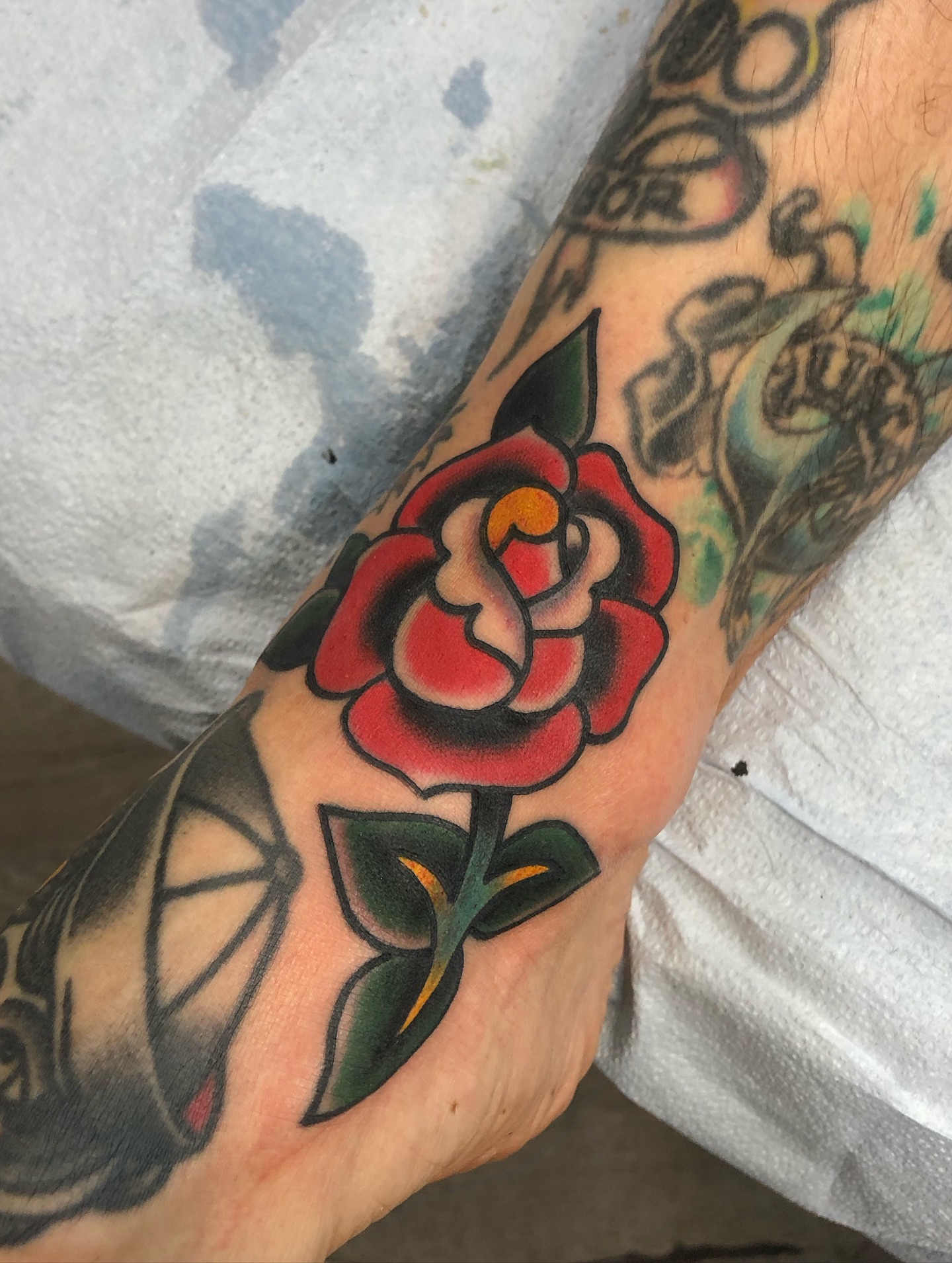 Red rose American traditional tattoo on the forearm by Nick Sharratt, Chicago, Illinois
