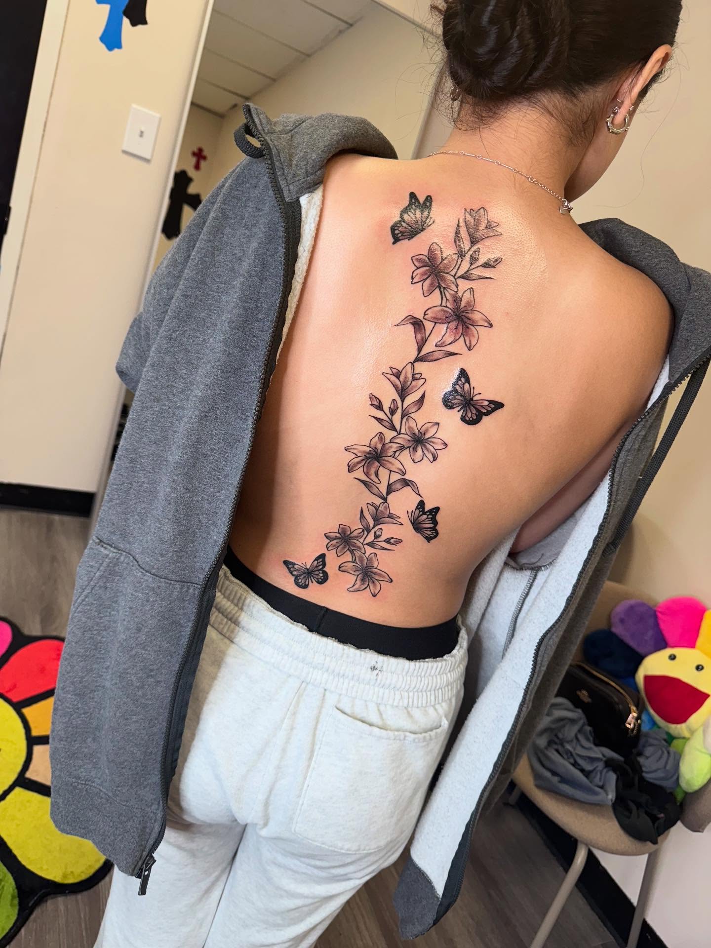 Flowers and butterflies black and grey tattoo on the back by Sierra 🩷